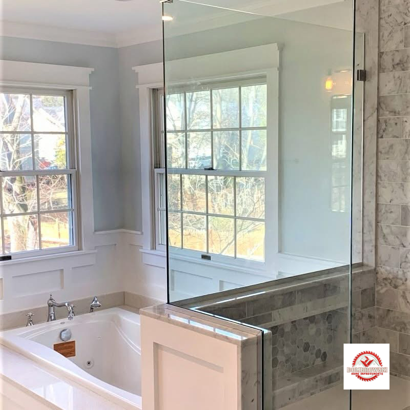 Corner view: soaking tub surround and frameless shower with wainscoting