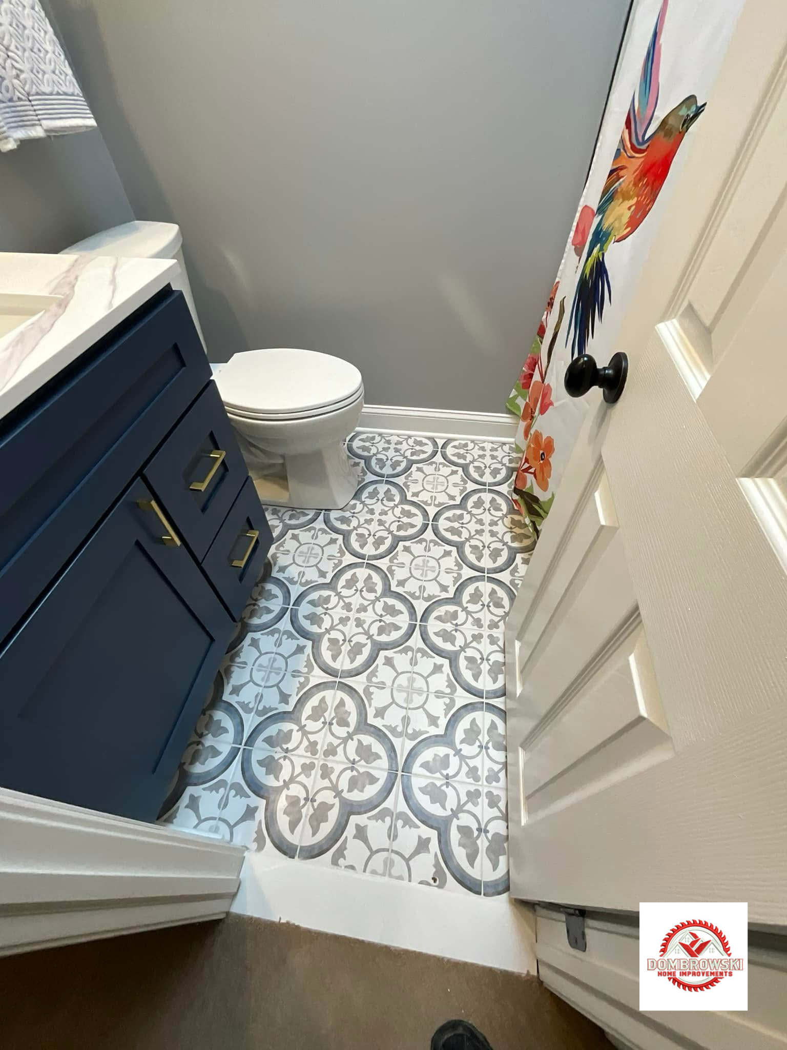 Navy blue vanity cabinet detail: gold hardware and decorative patterned floor tile