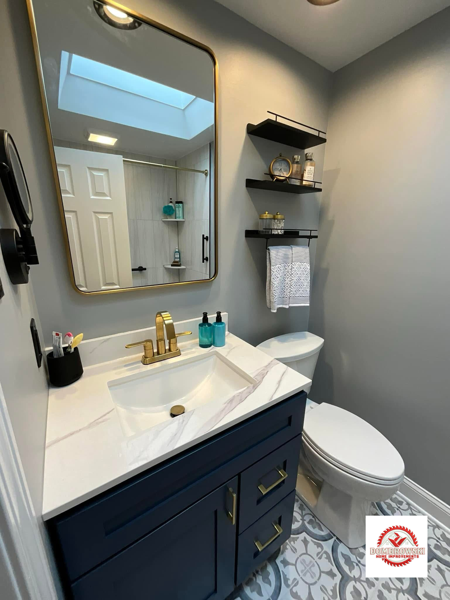 Navy blue vanity with gold hardware, quartz countertop and decorative floor tile