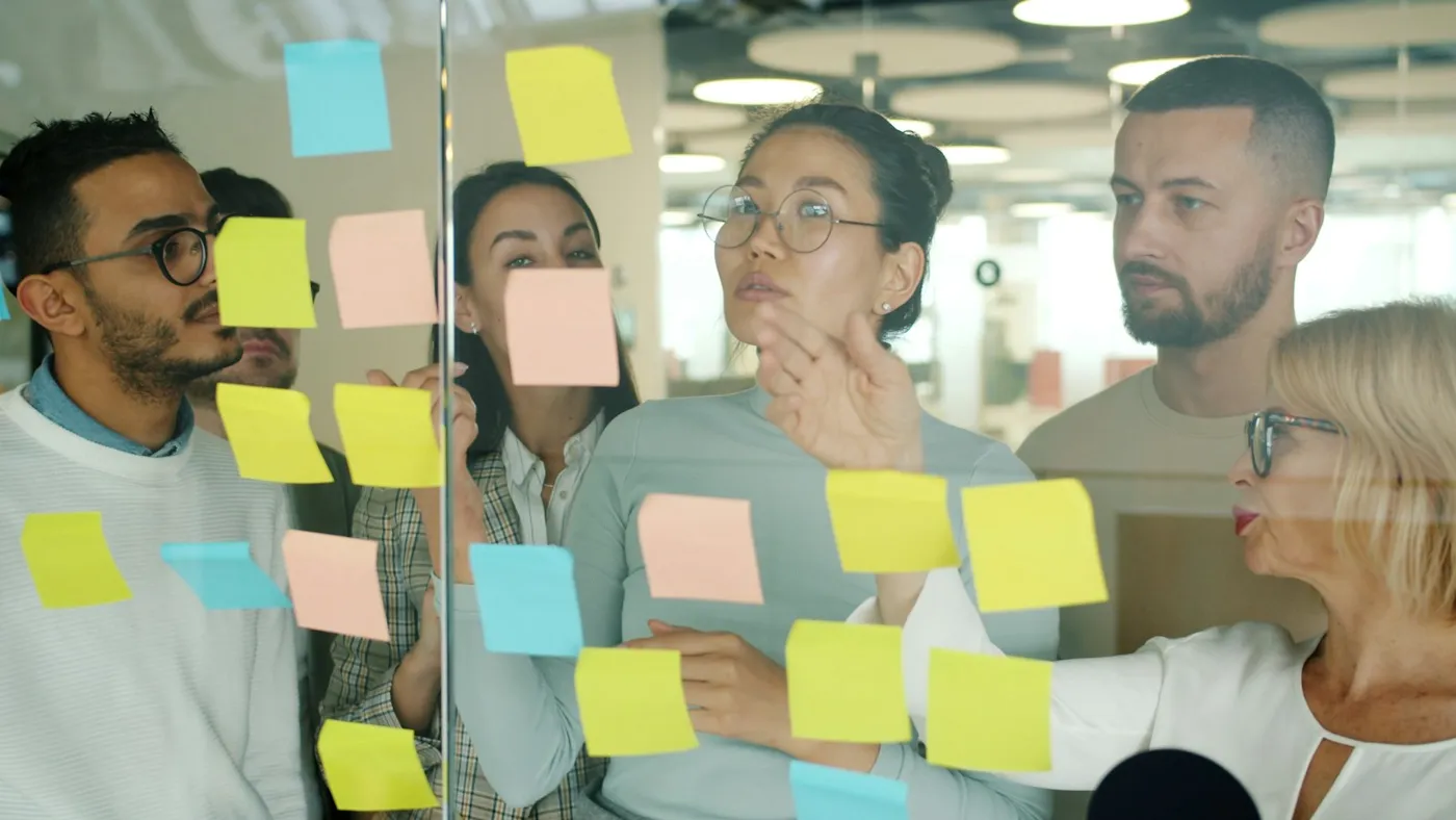 Colleagues working through ideas together at a wall of sticky notes