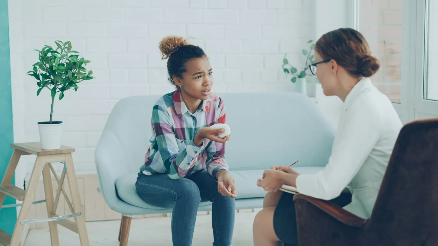 A counselor talking with a teenager in a bright office