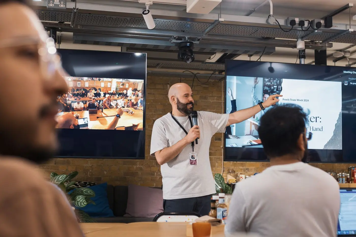 A team leader with a microphone presenting to a small group of colleagues in a bright, modern office
