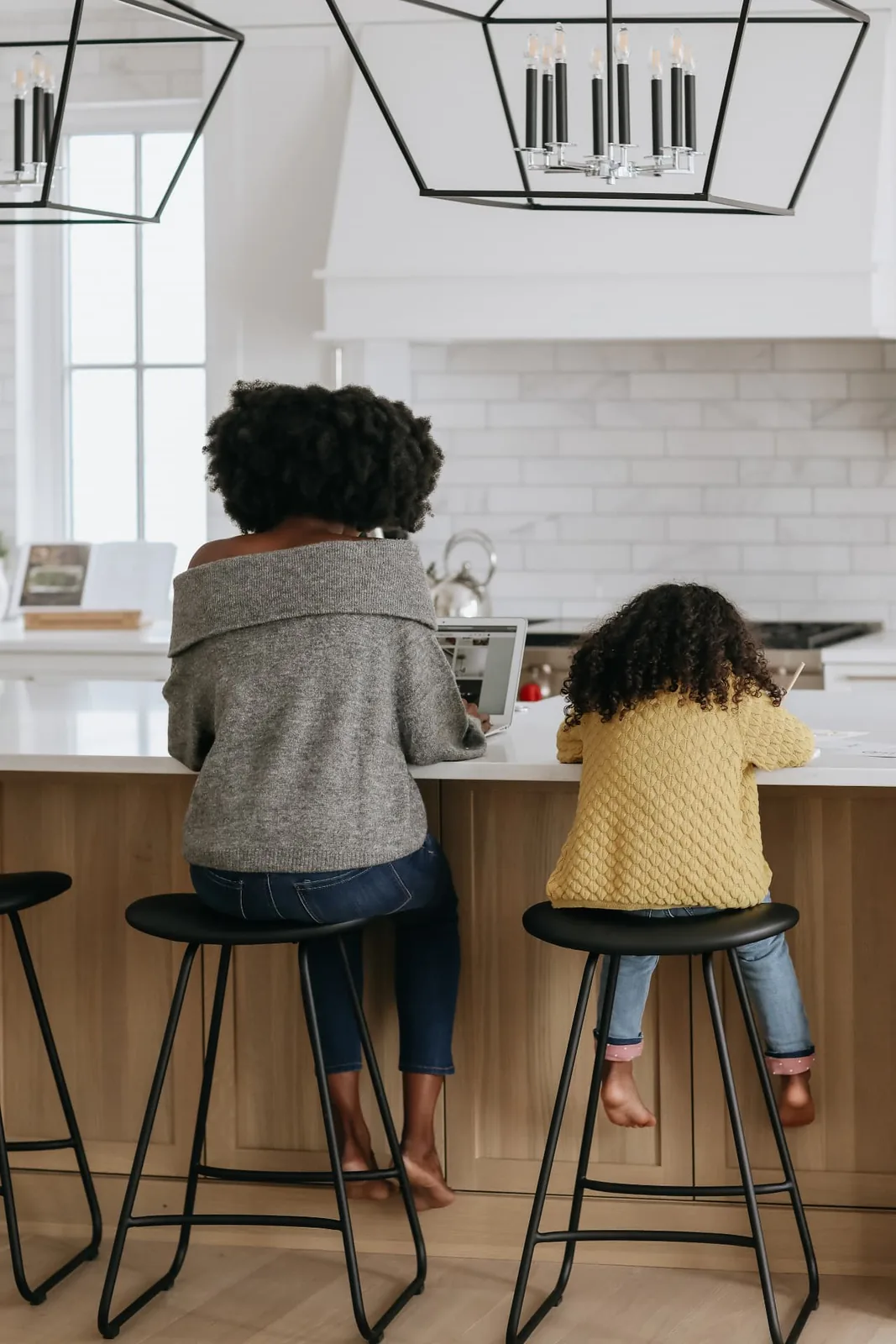 A mother and daughter side by side at a kitchen island, working and drawing together.