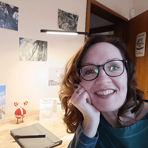 Katja sitzt an ihrem Schreibtisch mit Zeichentablet und Hoptimist, lächelt in die Kamera – offen für kreative Ideen und echte Verbindung.
