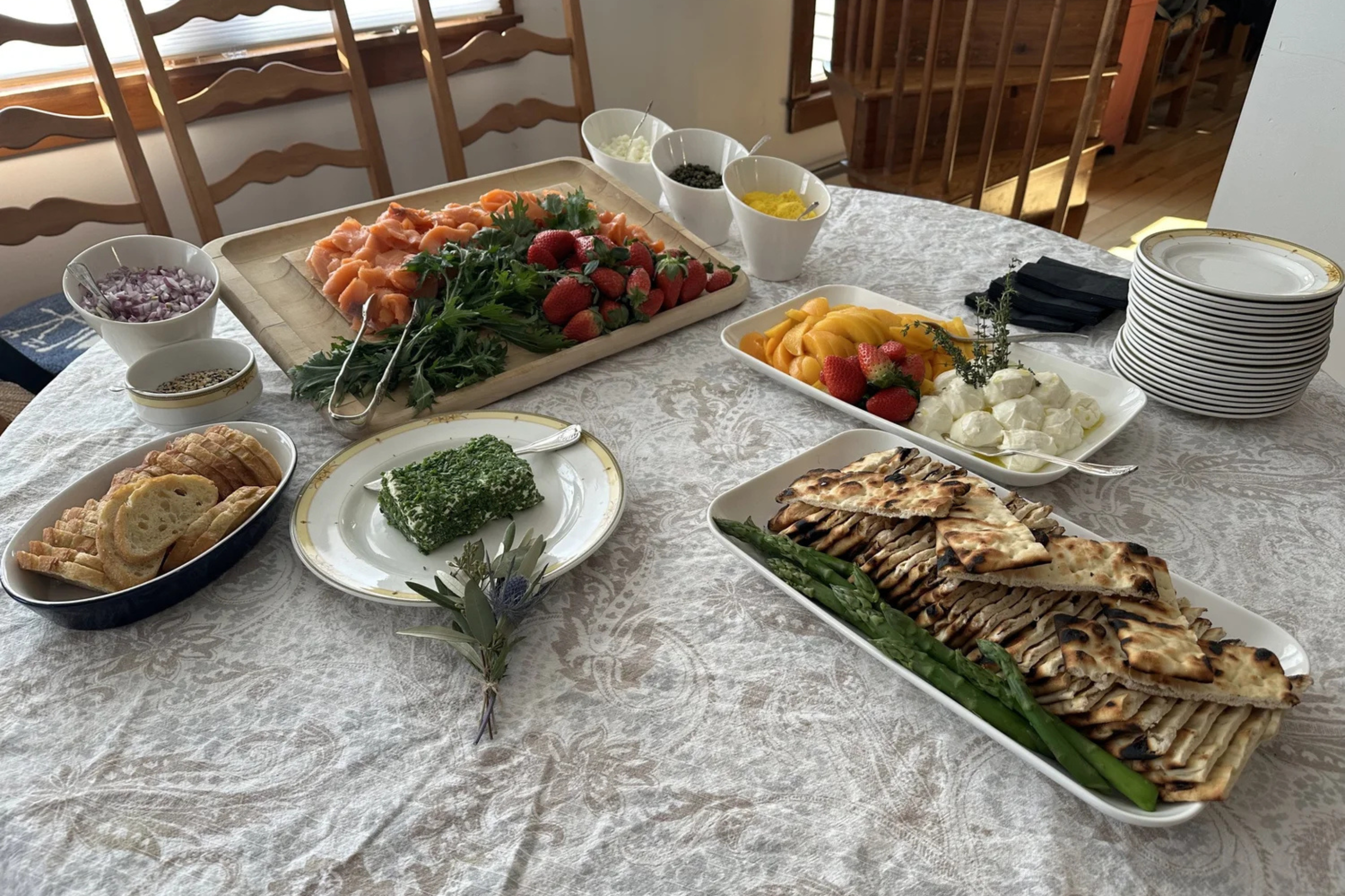 A gourmet buffet setup featuring fresh berries, local cheeses, and sliced meats catered for a coastal Maine vacation home gathering.