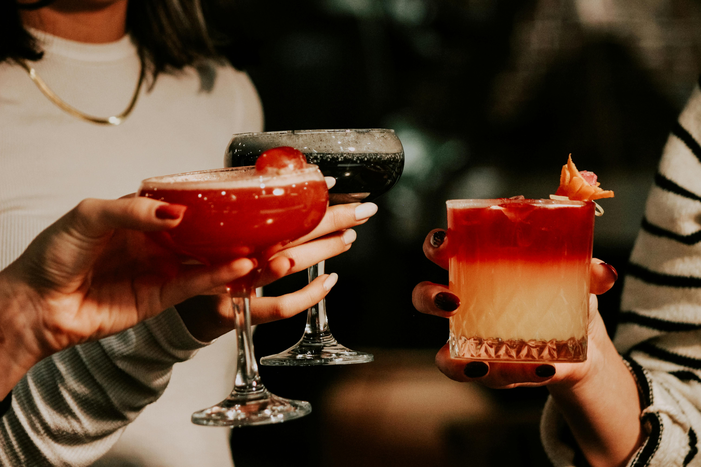 Guests raising glasses for a celebratory toast with vibrant handcrafted cocktails at a private party or anniversary celebration.