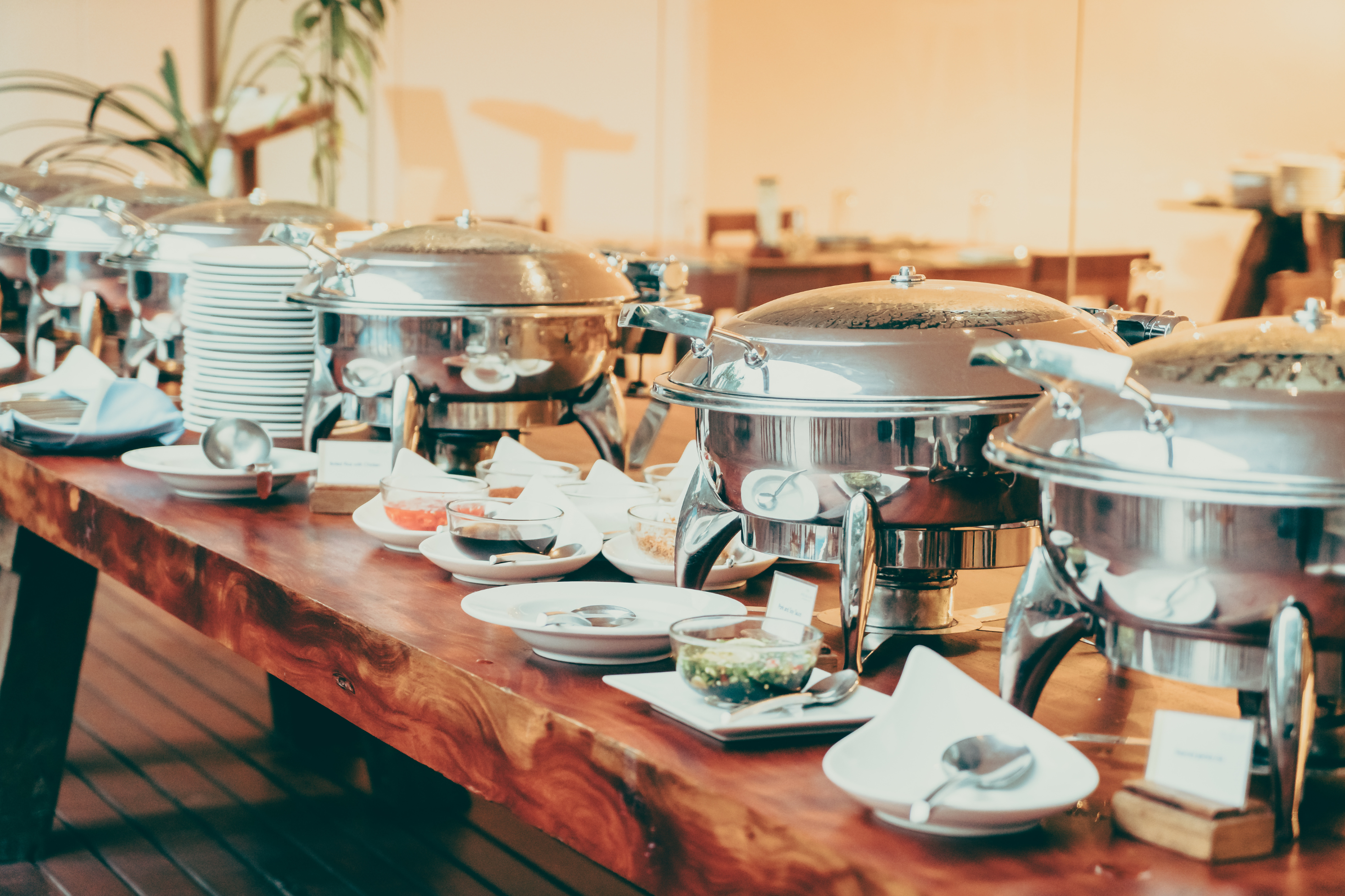 A rustic wooden table holding sleek, modern chafing dishes for community dinners, workshops, and nonprofit events in South Portland.