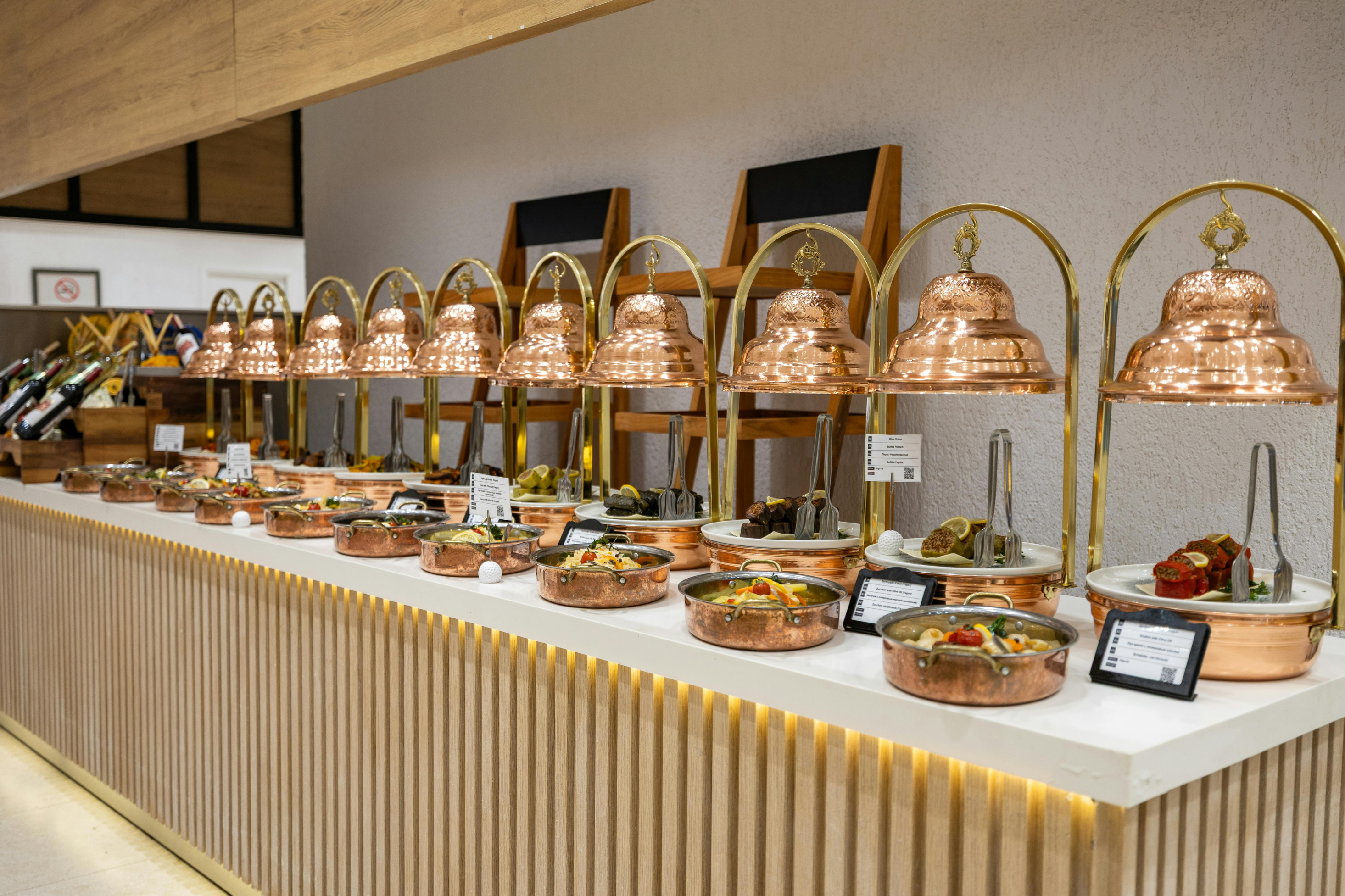 An elegant indoor food station with shining copper warmers, illustrating fully catered experiences available at Grateful Culinary Collaborations.