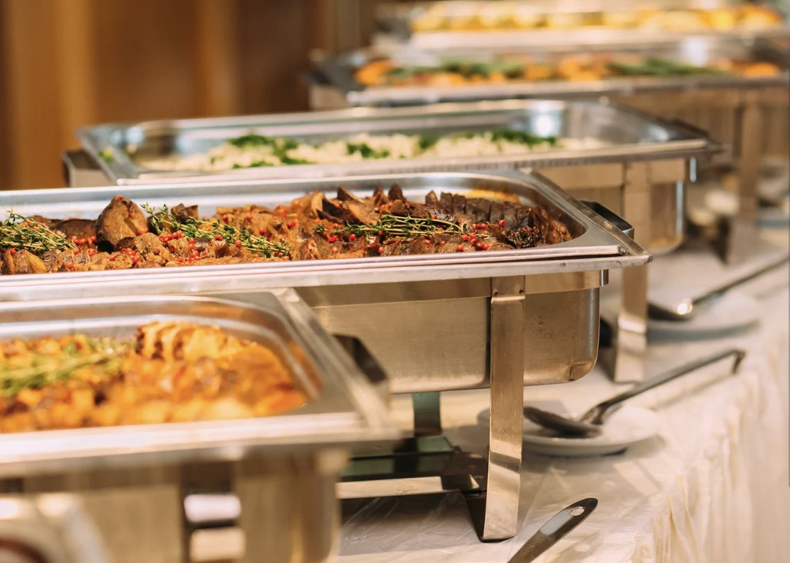 An elegant indoor food station with shining copper warmers, illustrating fully catered experiences available at Grateful Culinary Collaborations.