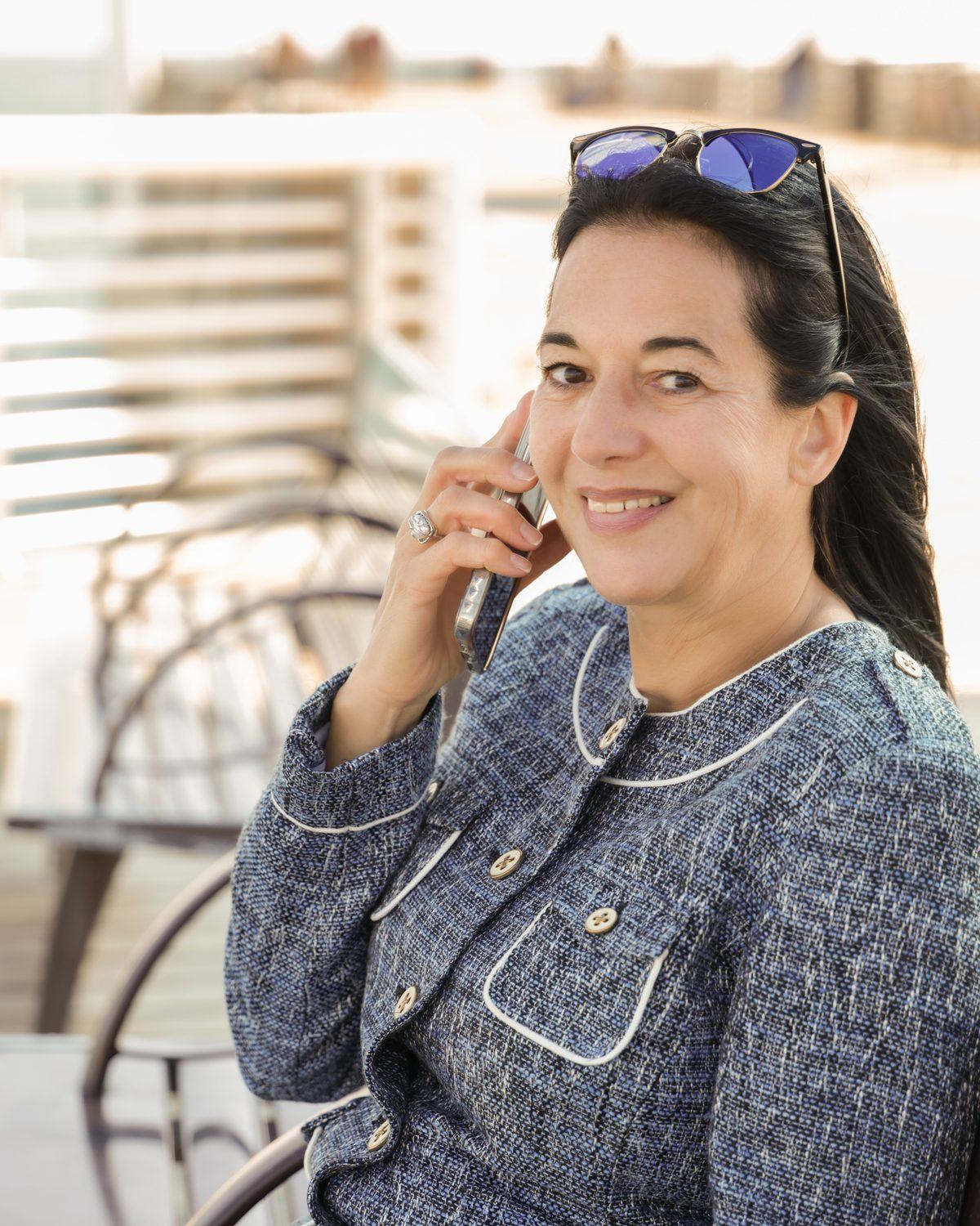 Annette on a bench, on the phone, smiling at the camera.