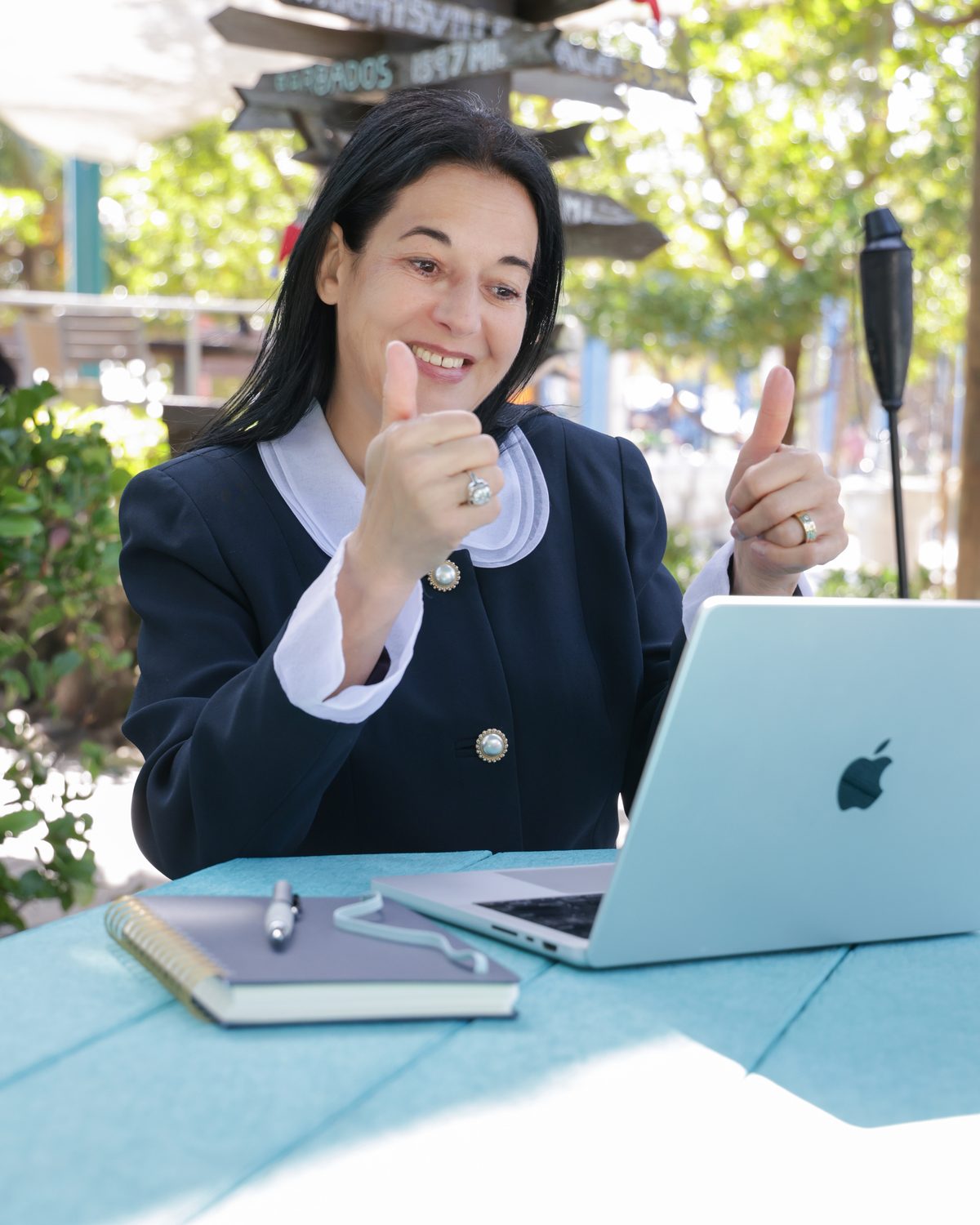 Annette at her laptop on a video call, giving two thumbs up.