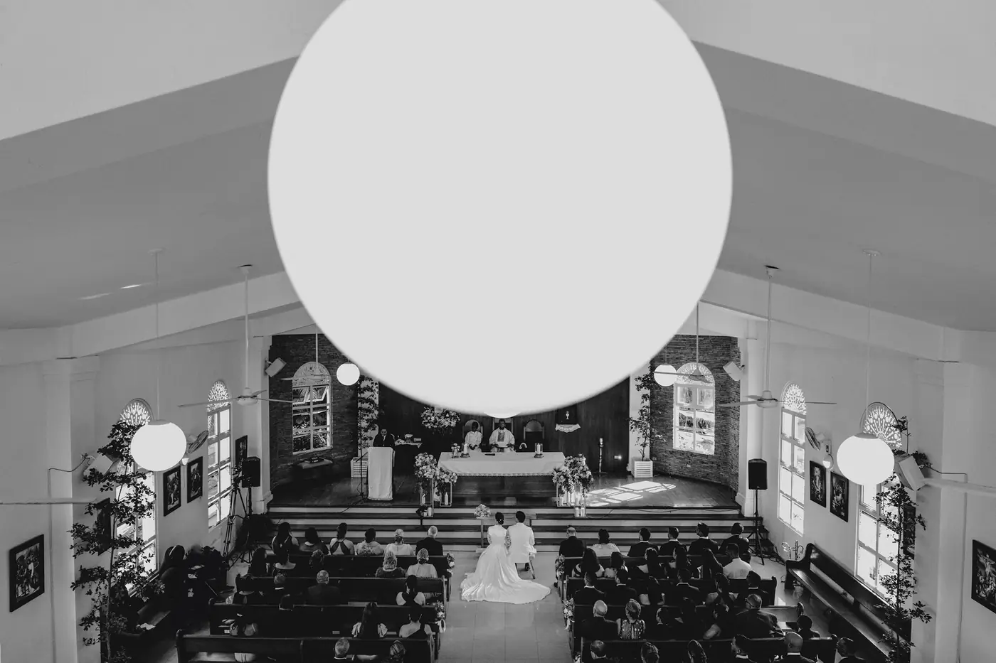 Vista a&eacute;rea de una iglesia durante la ceremonia, con una l&aacute;mpara redonda en primer plano