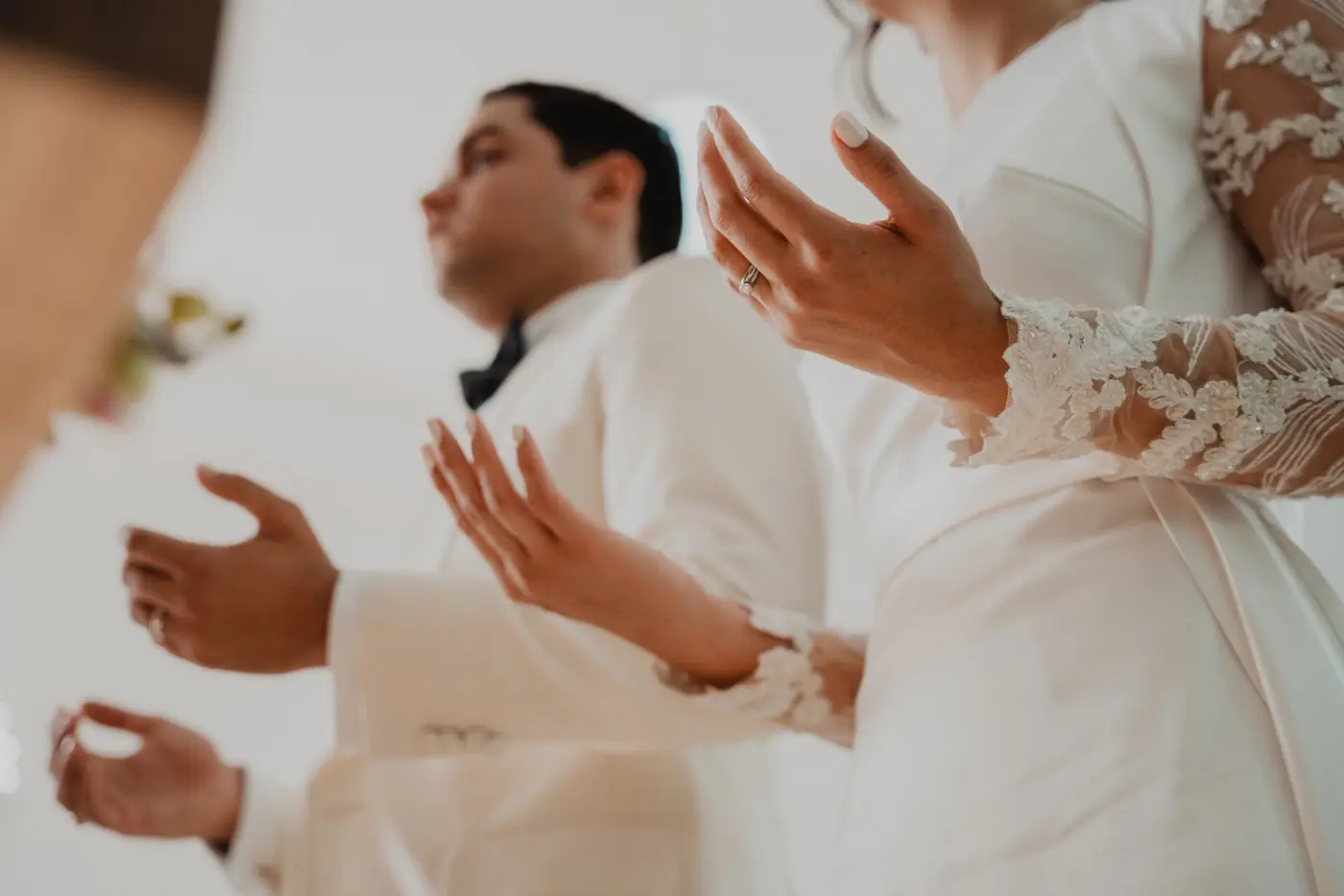 Las manos abiertas de los novios durante una oraci&oacute;n en la ceremonia
