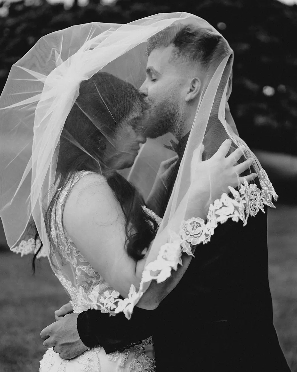 El novio besa la frente de la novia bajo el velo