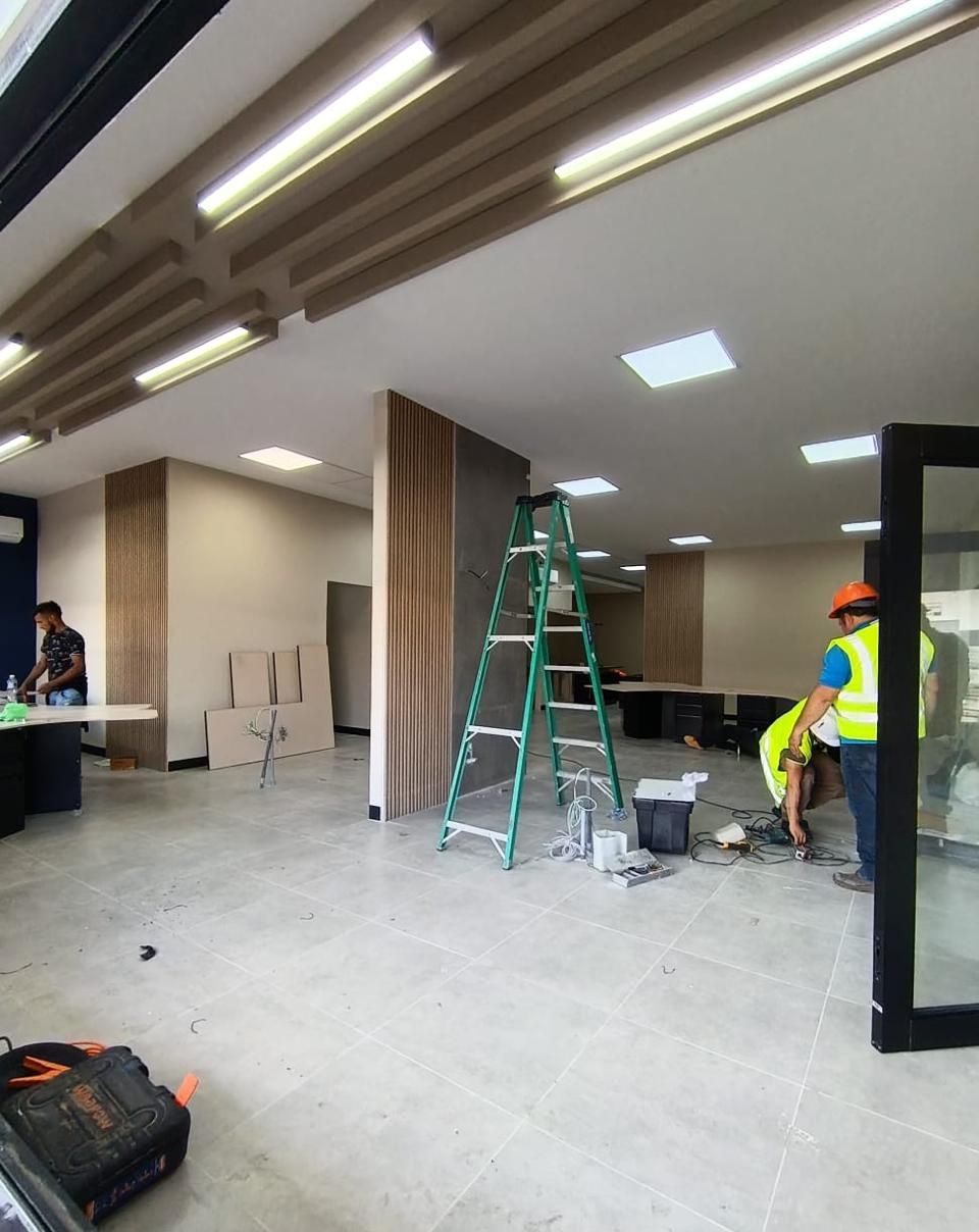 Cuadrilla en obra con escalera, instalando el panel de listones de madera del cielo