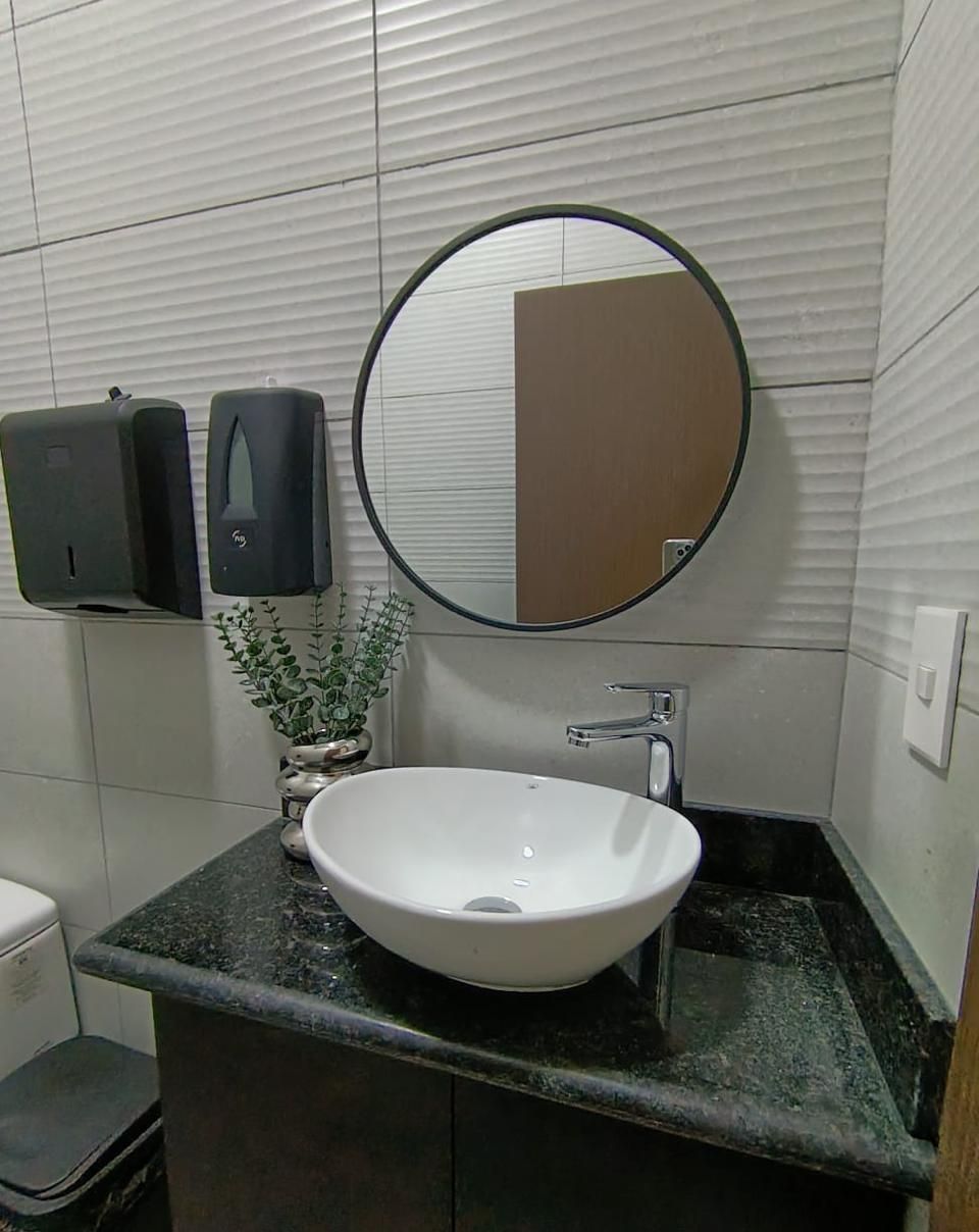 Baño de visitas con lavabo de sobreponer, cubierta de granito verde y espejo circular
