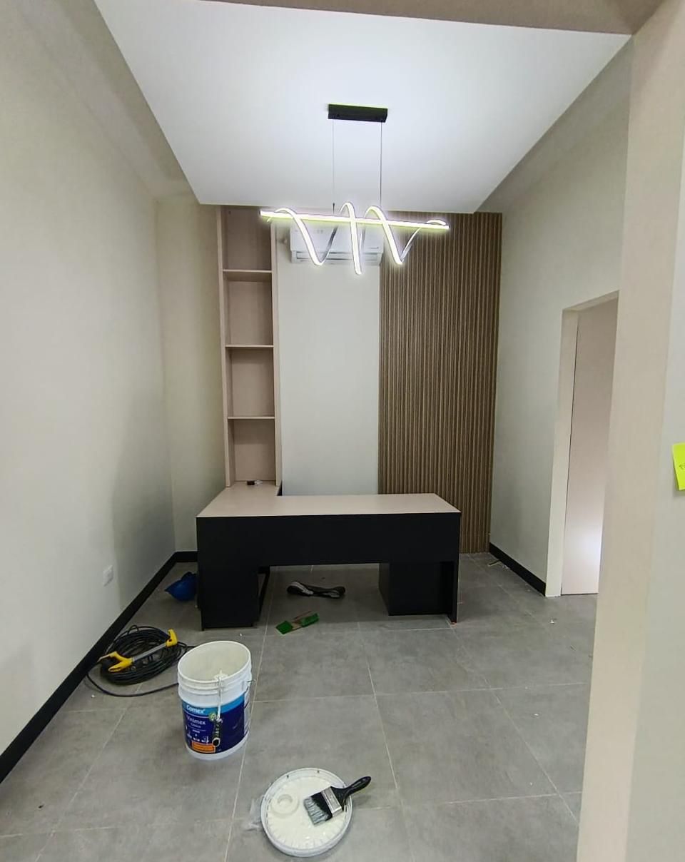 La misma oficina privada en fase de pintura, con cubeta y brocha en primer plano