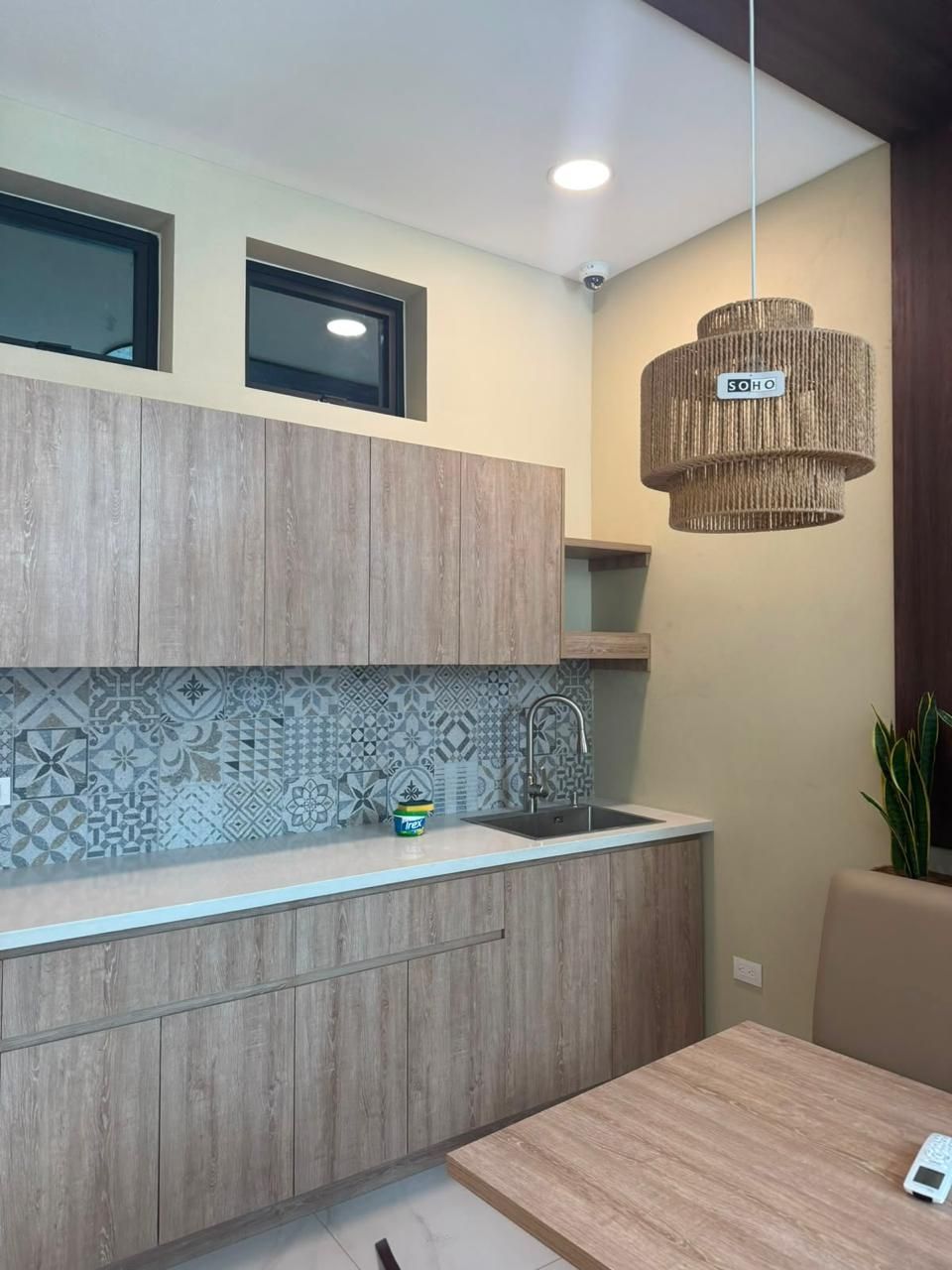 Cocina lineal de melamina roble claro con backsplash de mosaico de patrón y lámpara de fibra natural