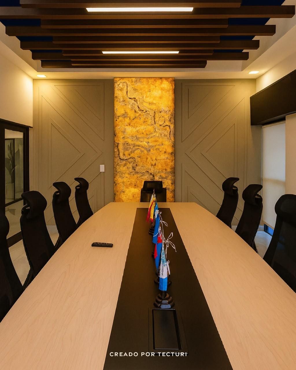 Sala de juntas con panel de ónix dorado retroiluminado, cielo de listones oscuros y mesa ejecutiva