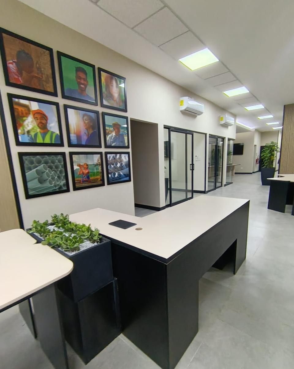 Pasillo de circulación con galería fotográfica enmarcada y oficinas de vidrio en perspectiva