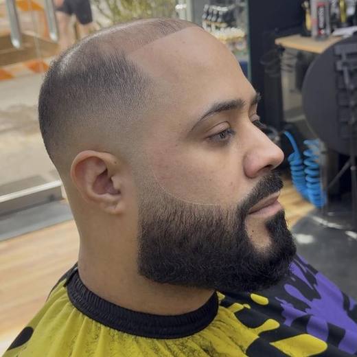 Skin fade with a shaped full beard and a sharp cheek line