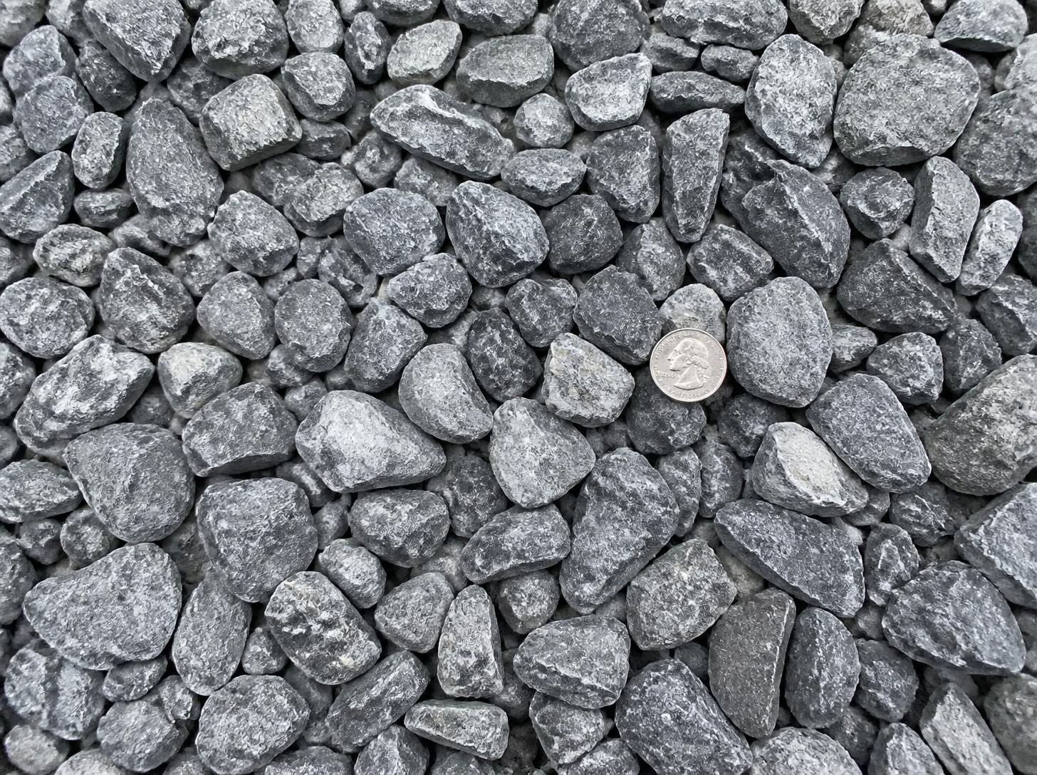 Close-up of 2-inch gray crushed limestone gravel with a quarter for scale