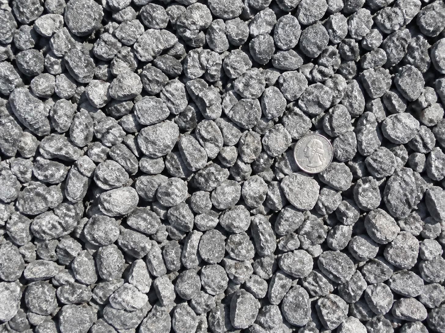 Close-up of #57 gray crushed stone with a quarter for scale
