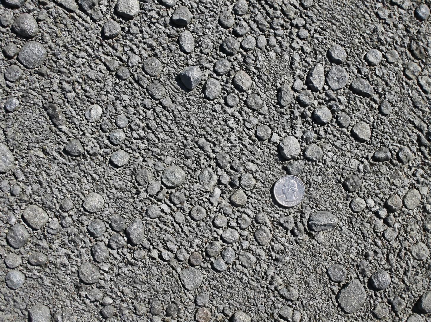 Close-up of compacted pug mix base stone with a quarter for scale