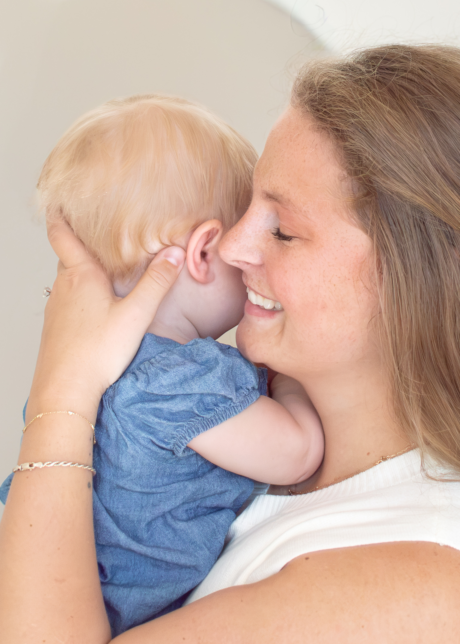 Dr. Keeley Brown smiling warmly while cradling a baby in her chiropractic office in Monument, Colorado