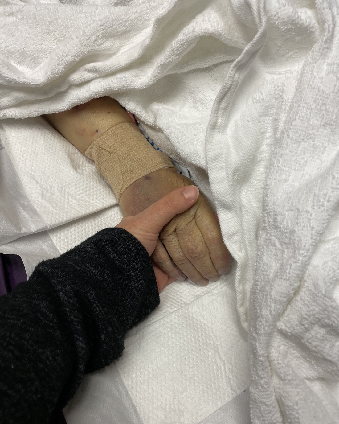 Victoria holding her grandmother's hand in hospital