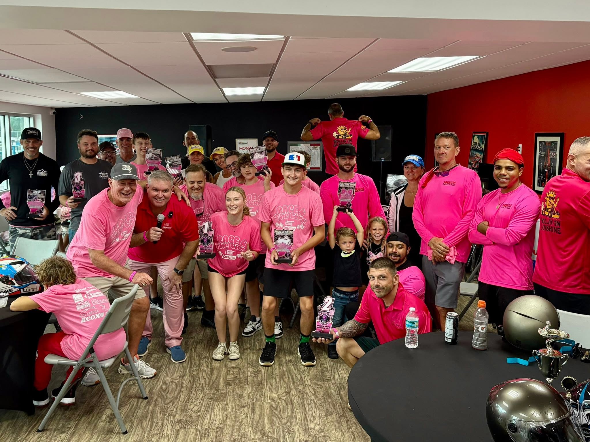 Winners and racers in pink shirts holding trophies at the 2025 Men Wear Pink Grand Prix at T4 KartPlex Raceway