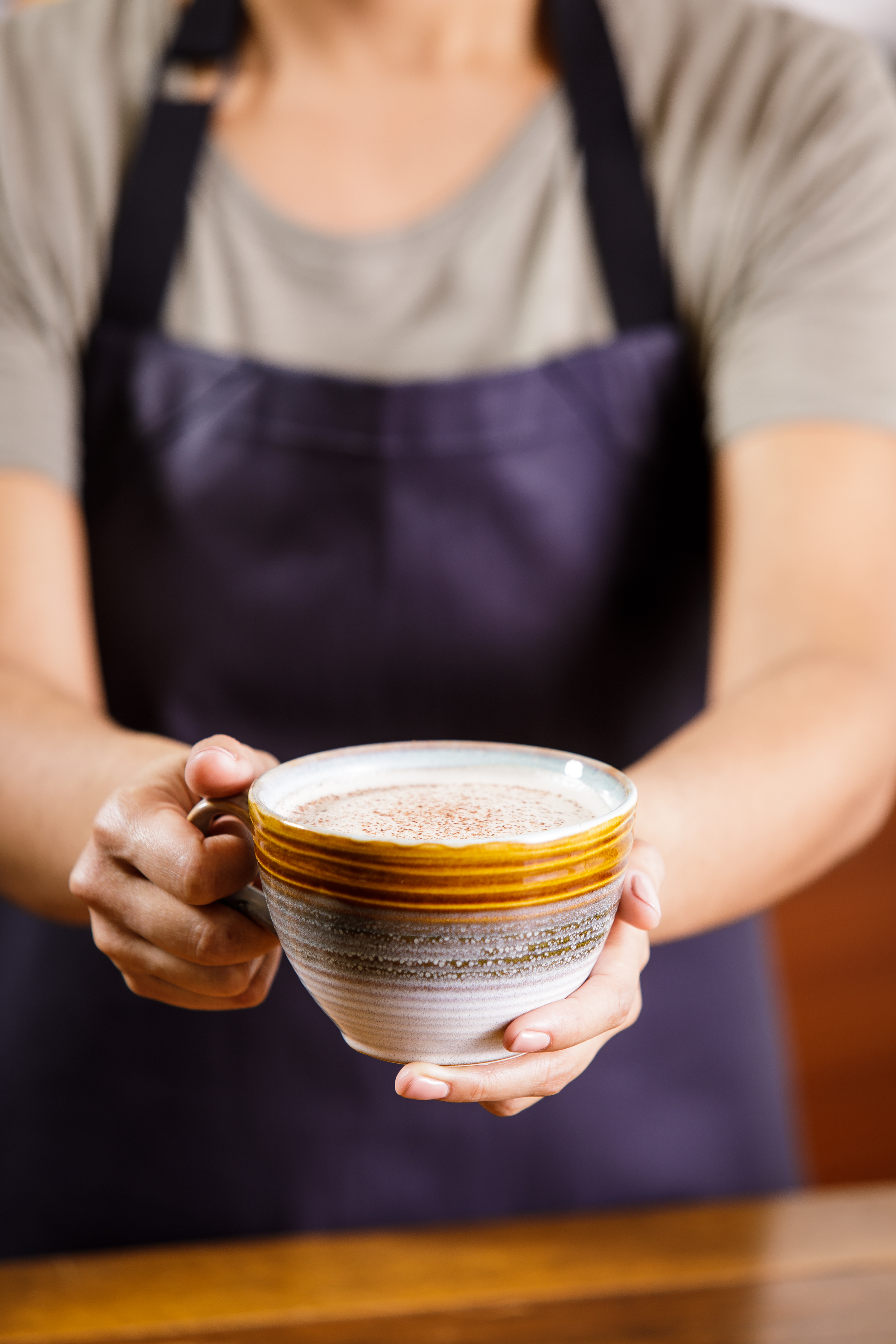 Professional beverage photography showing a barista holding a ceramic mug, highlighting hospitality, warmth, and brand experience.