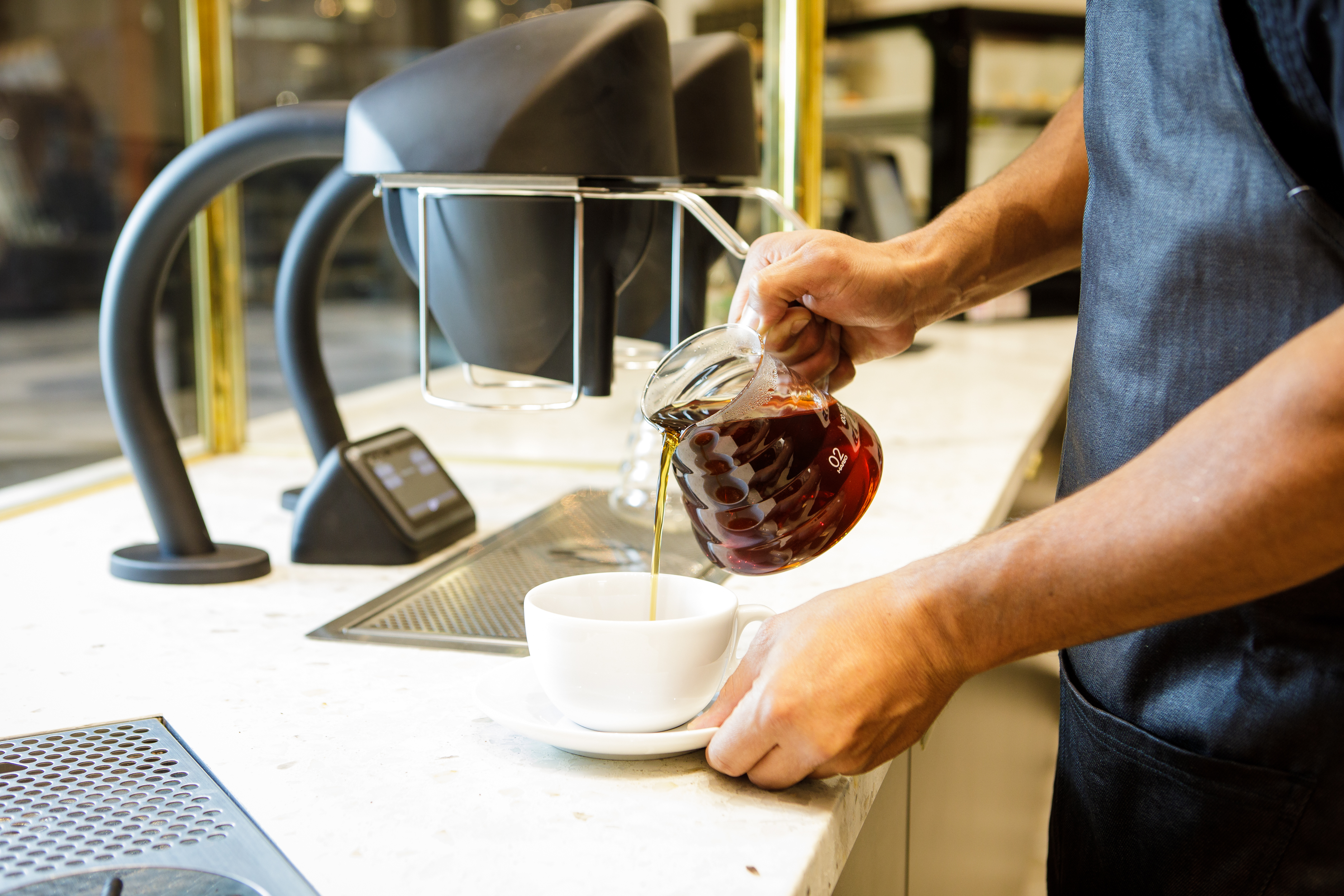 Professional beverage photography of a barista pouring coffee at a café counter, created for restaurant, café, and hospitality branding.