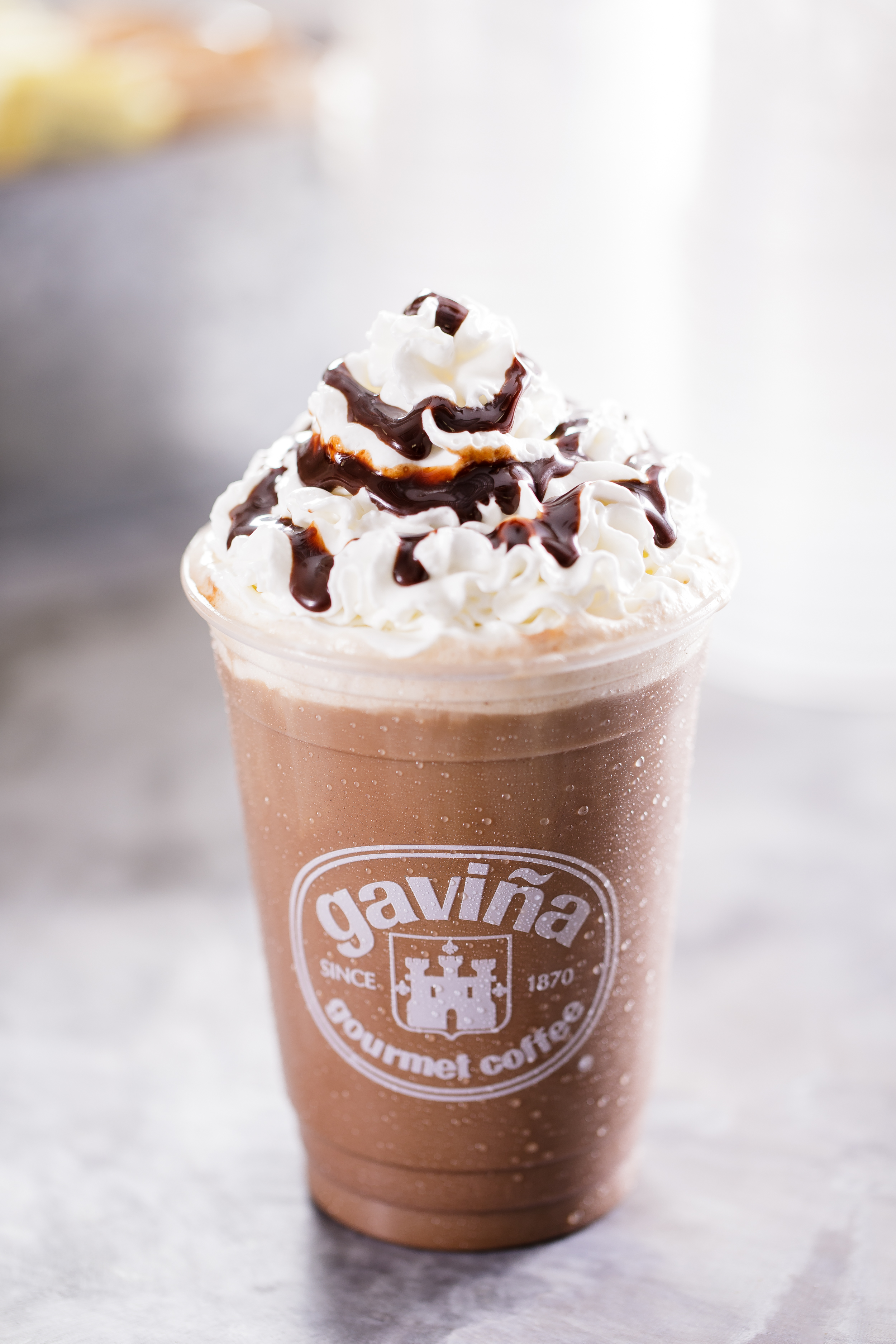 Commercial beverage photography of a blended iced coffee topped with whipped cream and chocolate drizzle, created for coffee brand and café marketing.