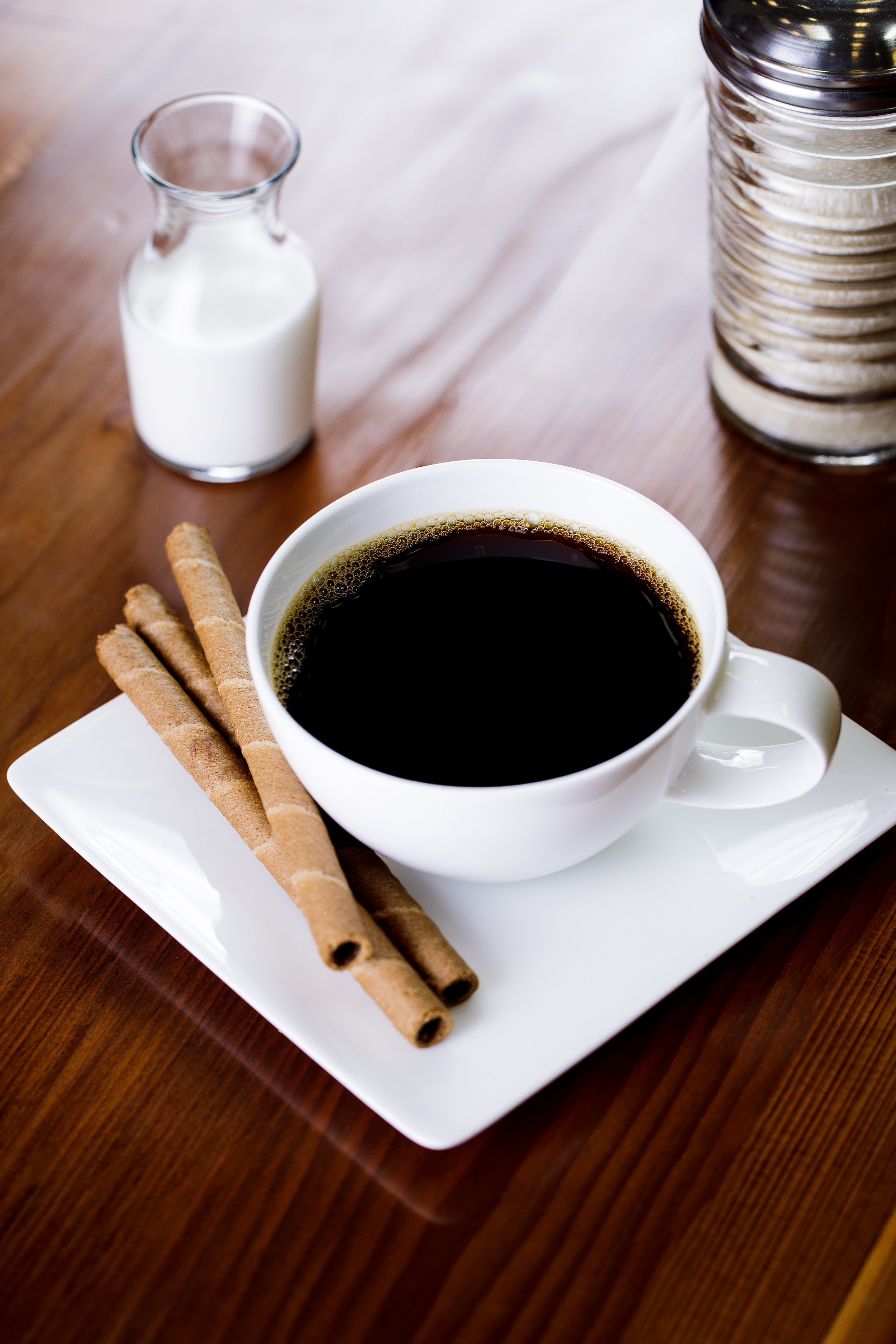 Styled coffee photography featuring a cup of black coffee with Pirouline cookies, photographed for café menus and beverage brand marketing.