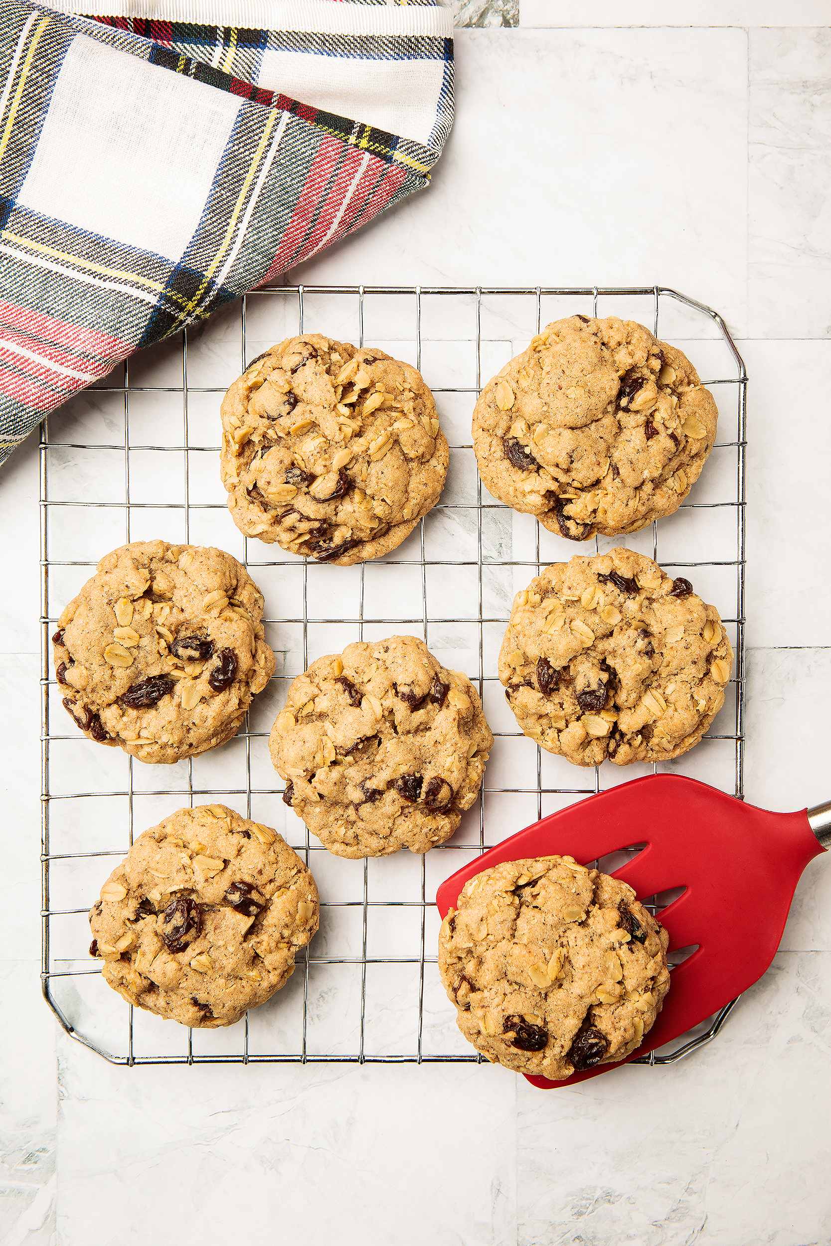 Freshly baked vegan oatmeal chocolate chip cookies on a cooling rack with a holiday towel, created for a Christmas cookie cookbook.