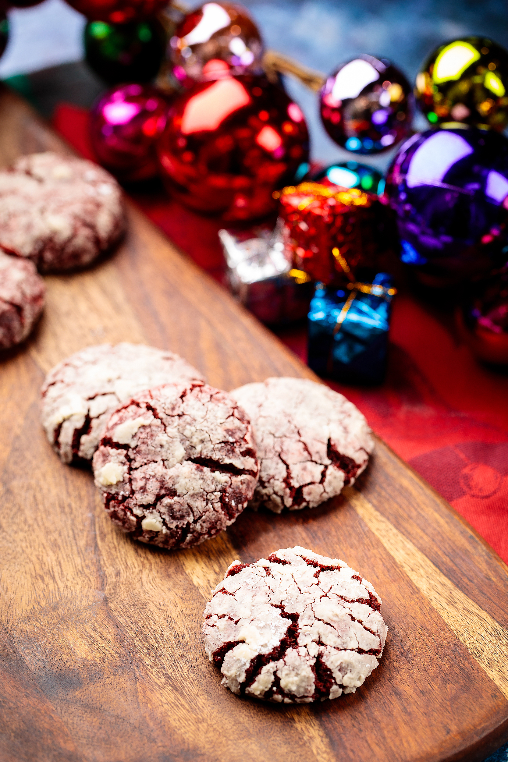 Vegan chocolate crinkle cookies styled with colorful Christmas ornaments for a festive cookbook photo spread.