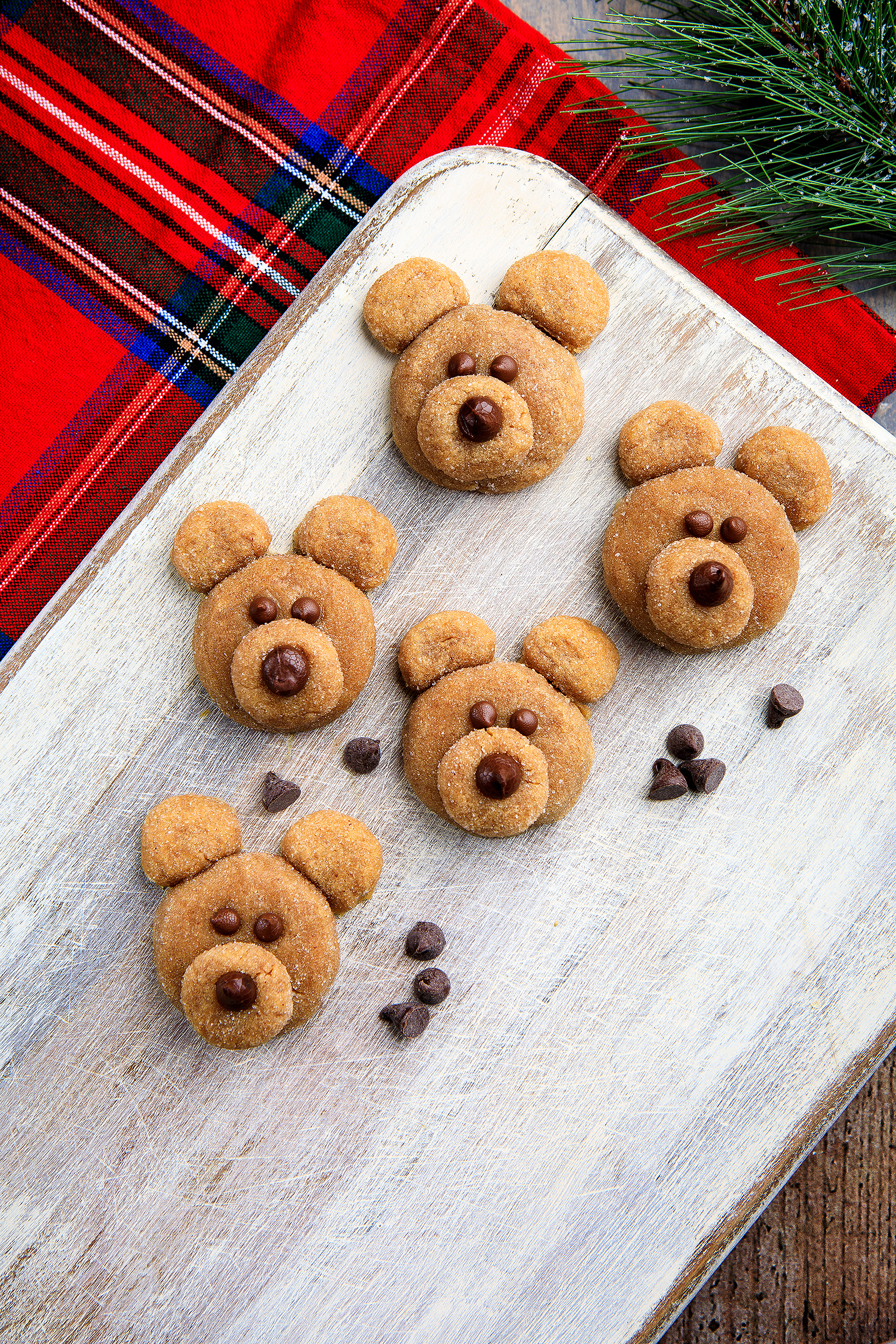 Cute vegan teddy bear cookies photographed on a winter plaid backdrop for Audrey Dunham’s Vegan Christmas Cookies & Cocoa cookbook.
