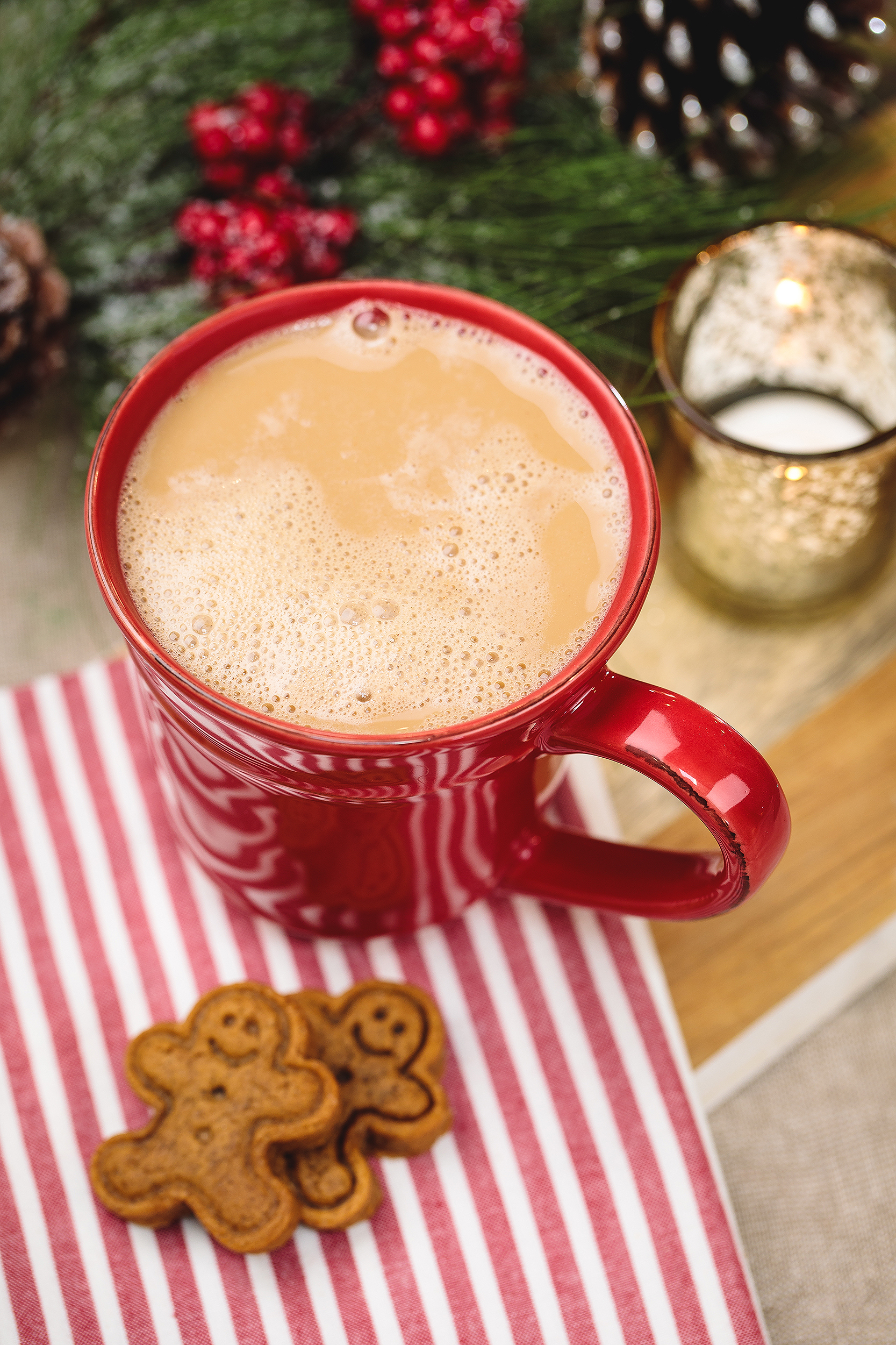 Red holiday mug of vegan cocoa with mini gingerbread cookies on a striped napkin, captured for a vegan Christmas cookbook.