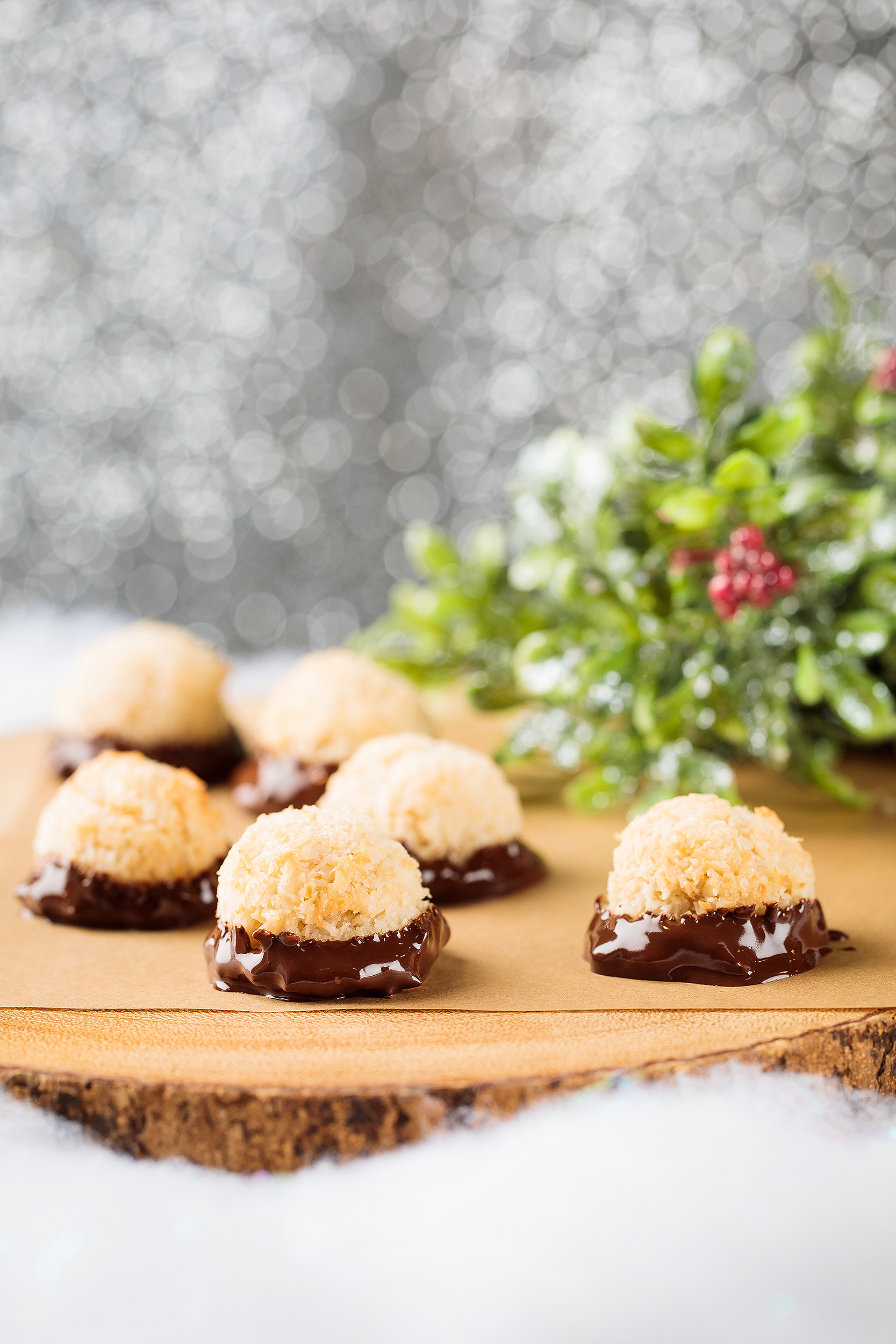 Vegan chocolate-dipped coconut macaroons styled in a snowy Christmas setting for a holiday cookie cookbook.