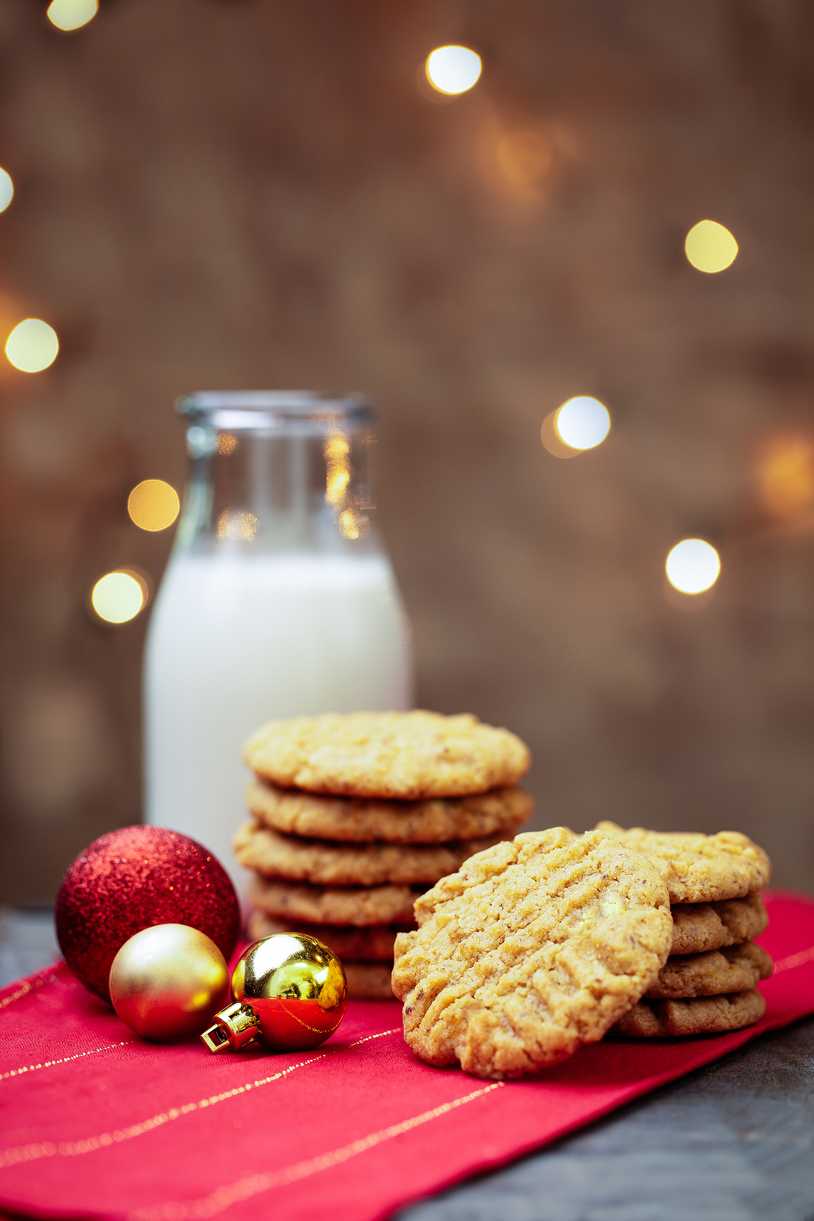 Vegan peanut butter cookies photographed with holiday ornaments and a bottle of dairy-free milk for Audrey Dunham’s Vegan Christmas Cookies & Cocoa cookbook.