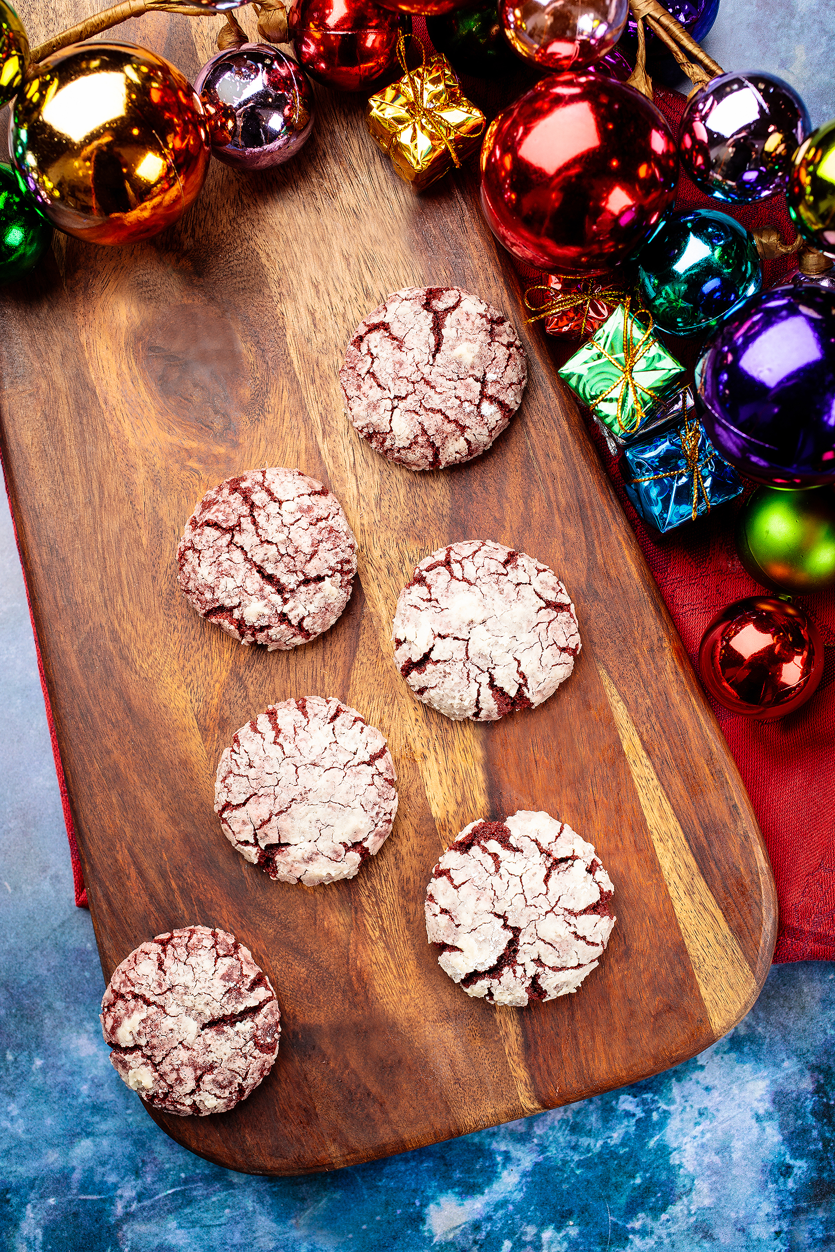 Festive vegan chocolate crinkle cookies styled with colorful ornaments for a holiday dessert cookbook photoshoot.