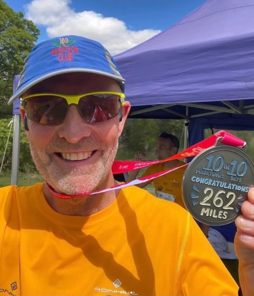 Dave holding his medal for ten marathons in ten days, 262 miles