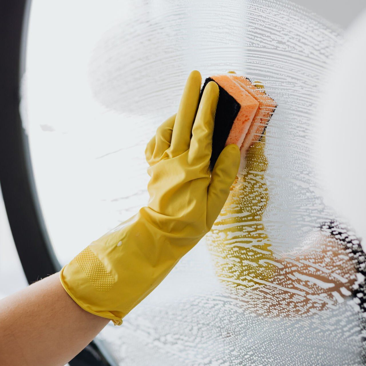 Gloved hand wiping a mirror during a deep cleaning job in Wolfforth, TX