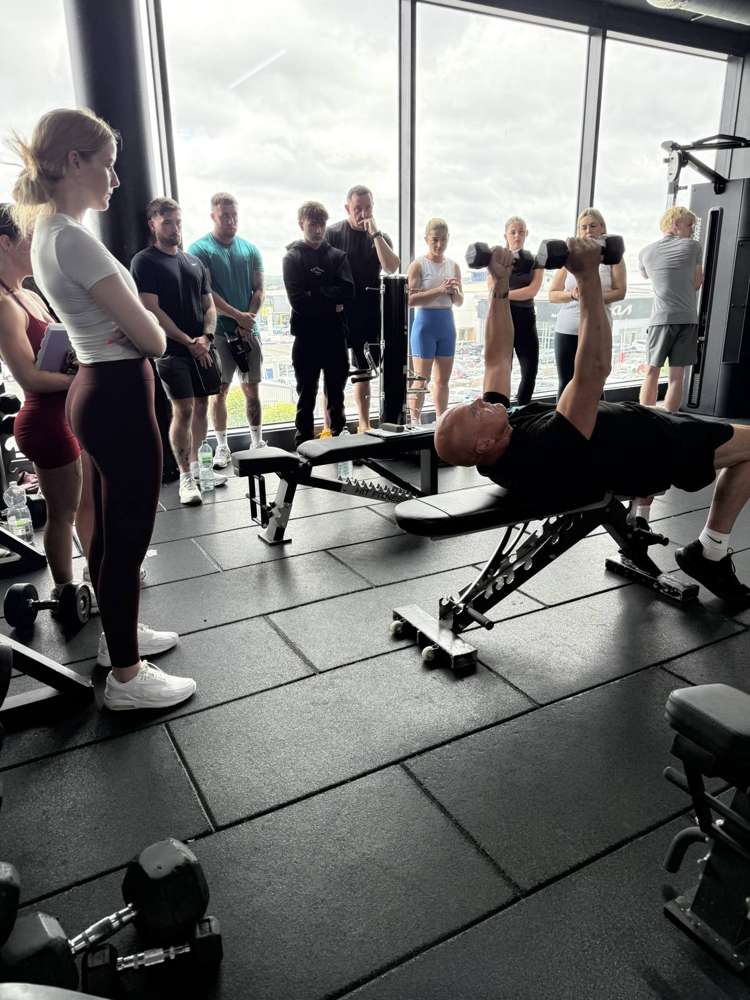 Course tutor demonstrating coaching technique to PT students during an in-person practical workshop