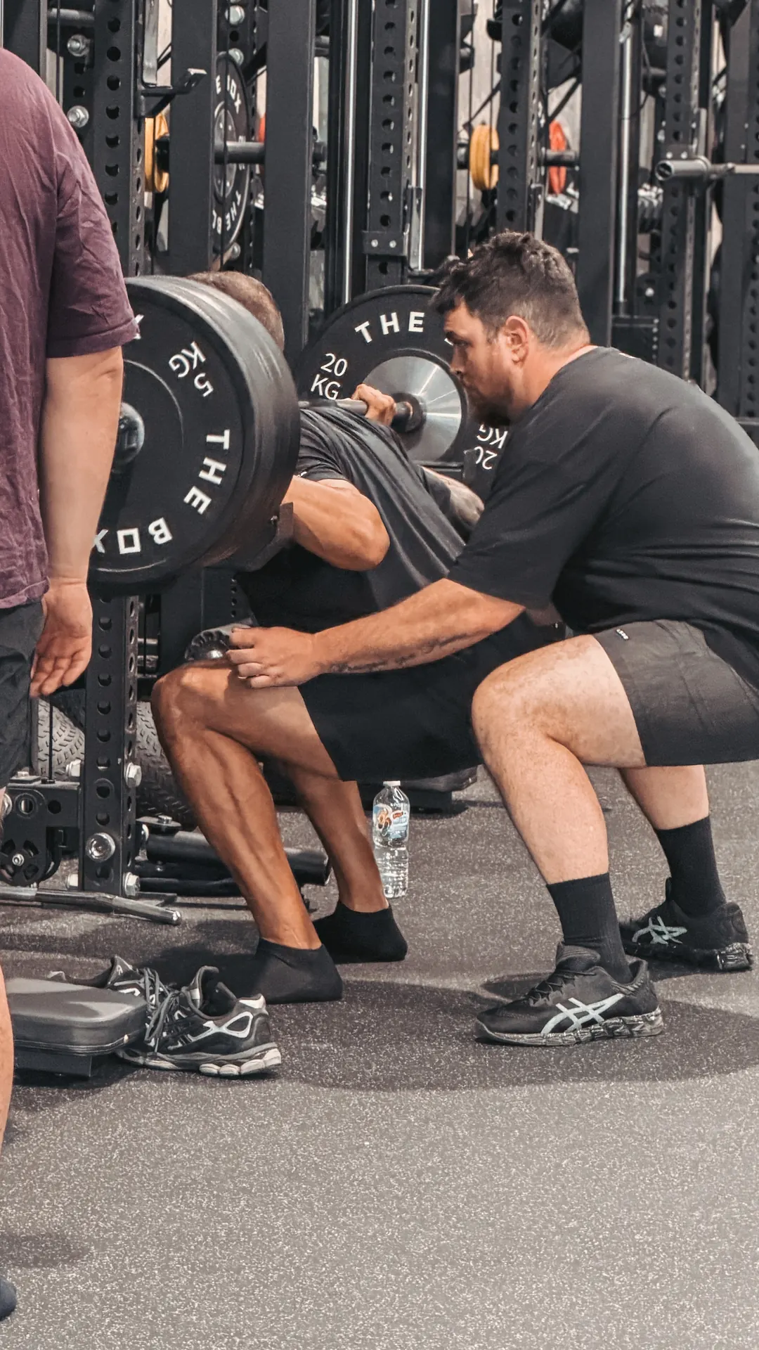 Coach giving a member a hands-on squat cue at The Box