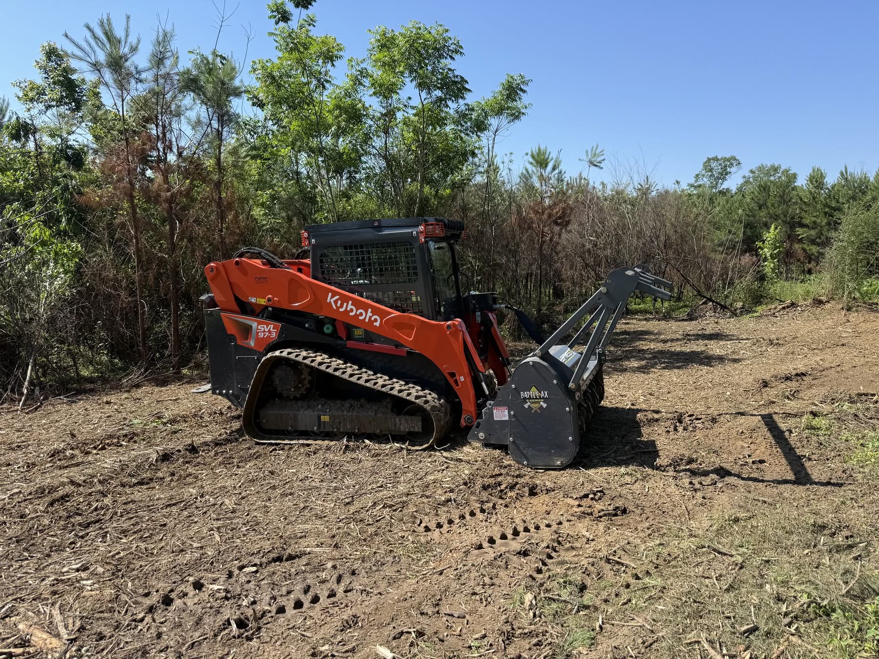 Kubota SVL97-3 compact track loader with its forestry mulching head, sitting on fresh mulch