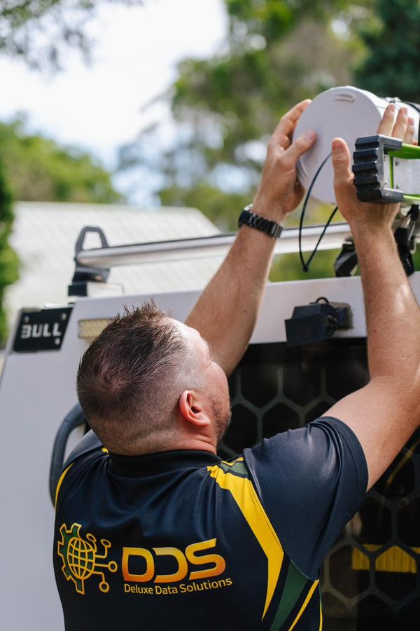 DDS technician on ladder installing security camera at residential property