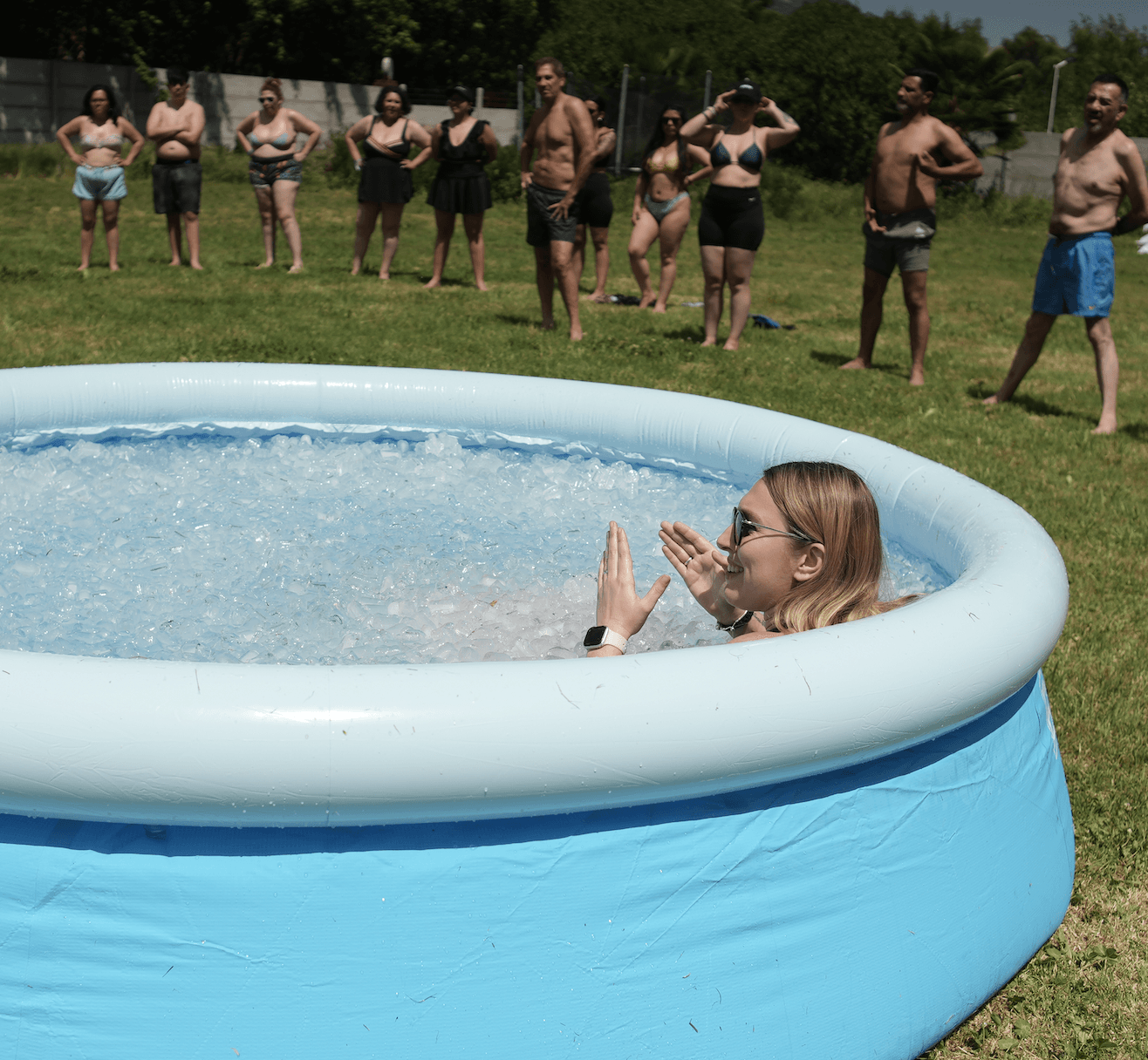 Participante en una piscina de hielo al aire libre, con el grupo observando alrededor