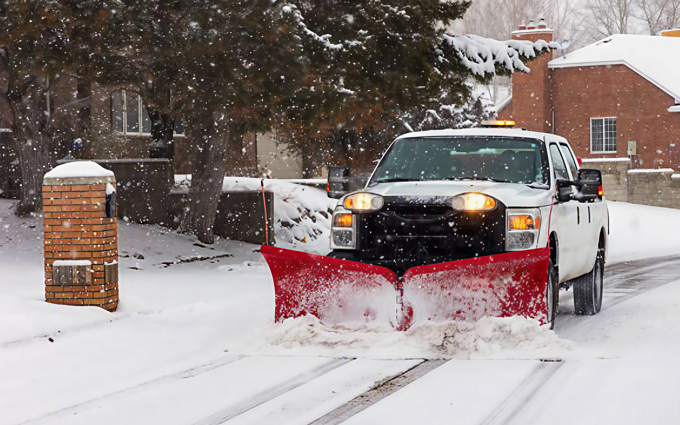 Snow removal near me truck with a red V plow clearing a neighborhood street